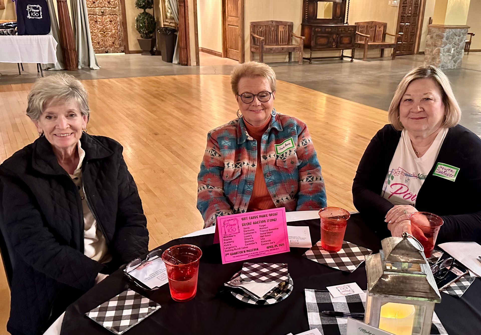 Three older women are sitting at a table with drinks.