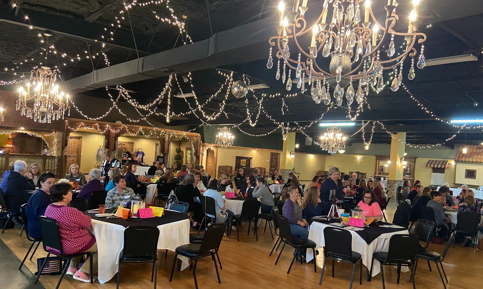 A large group of people are sitting at tables in a large room.