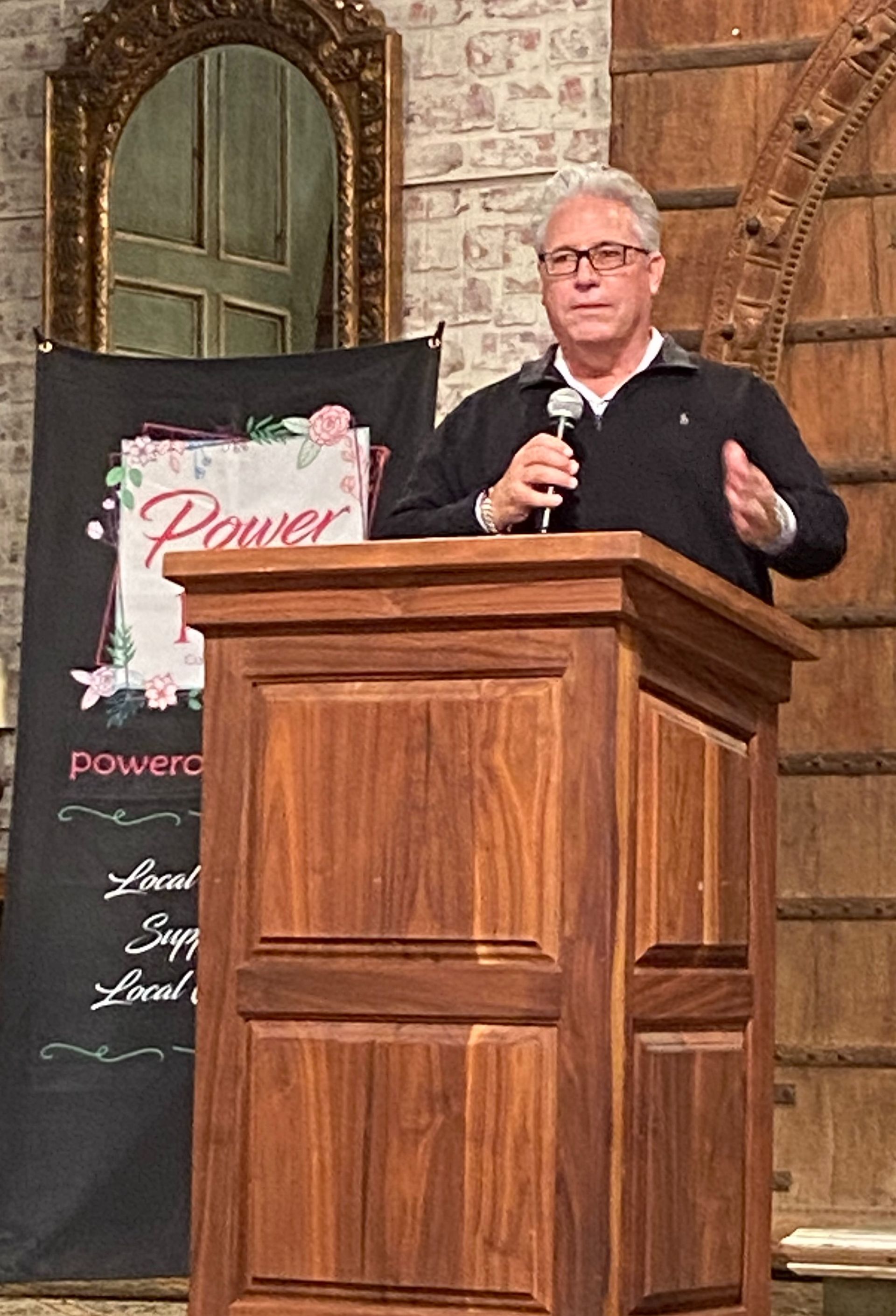 A man is standing at a podium holding a microphone.