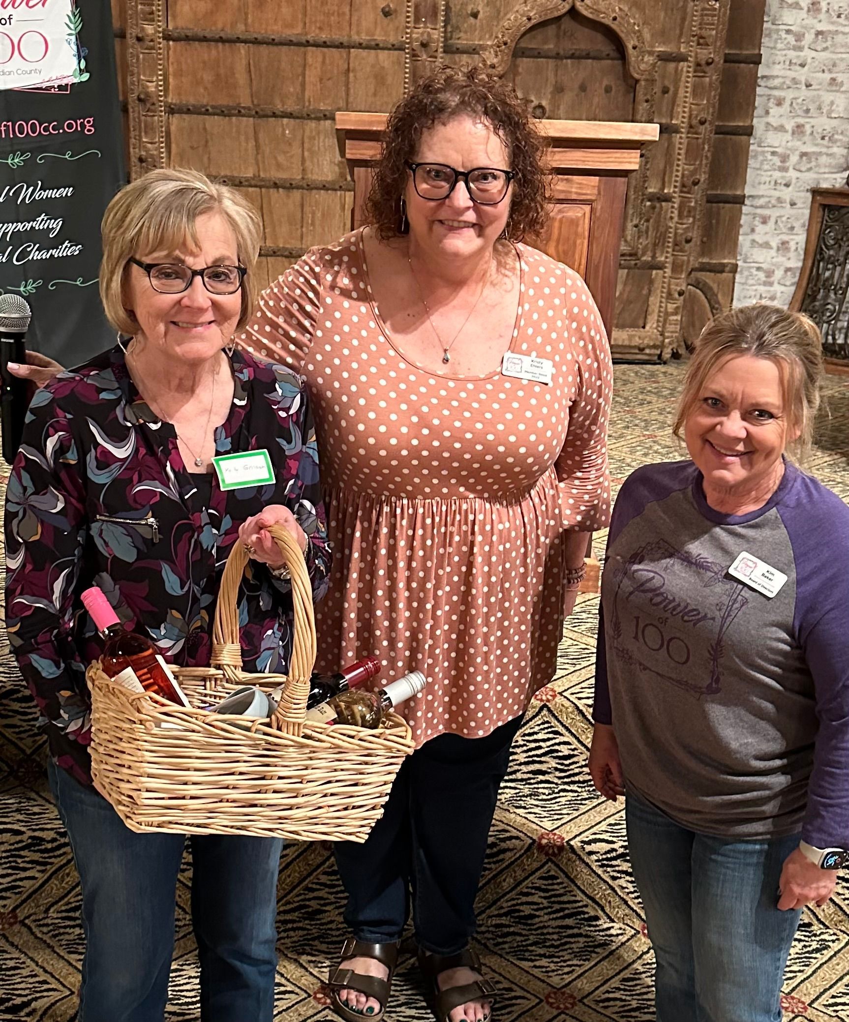 Three women are standing next to each other holding baskets of wine.