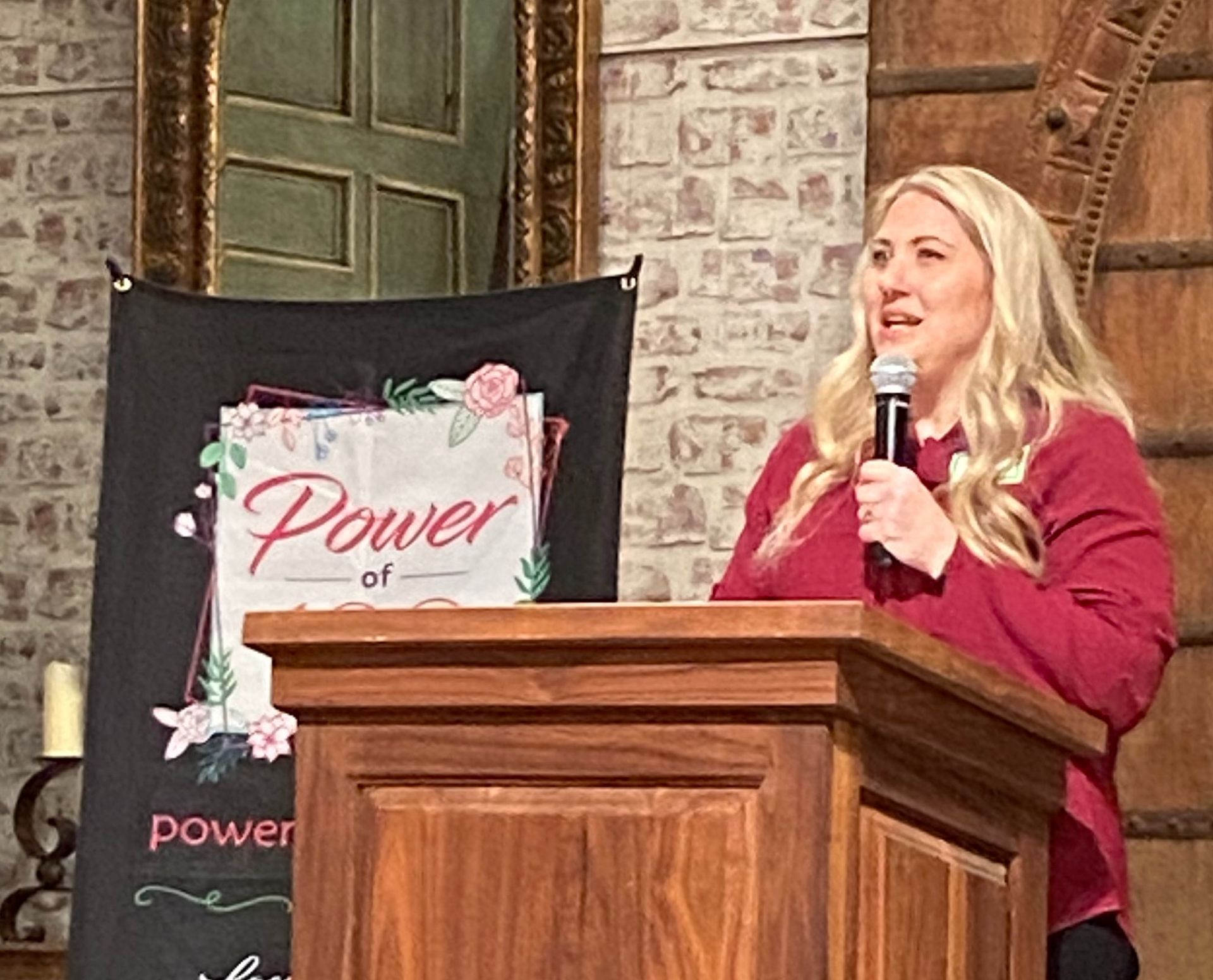 A woman is standing at a podium holding a microphone.