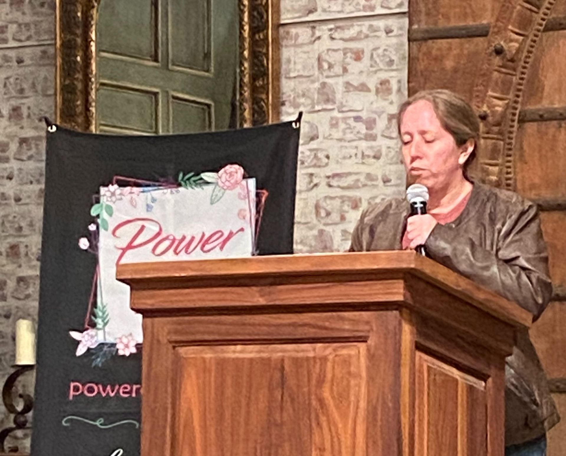 A woman is standing at a podium holding a microphone.