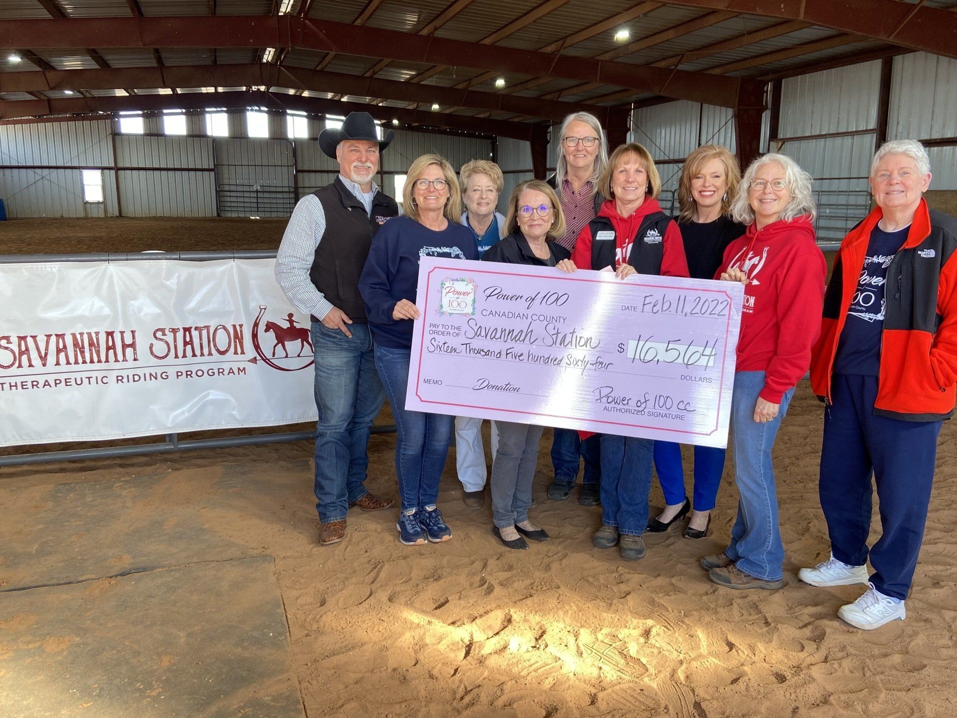 A group of people are standing in a barn holding a large check.