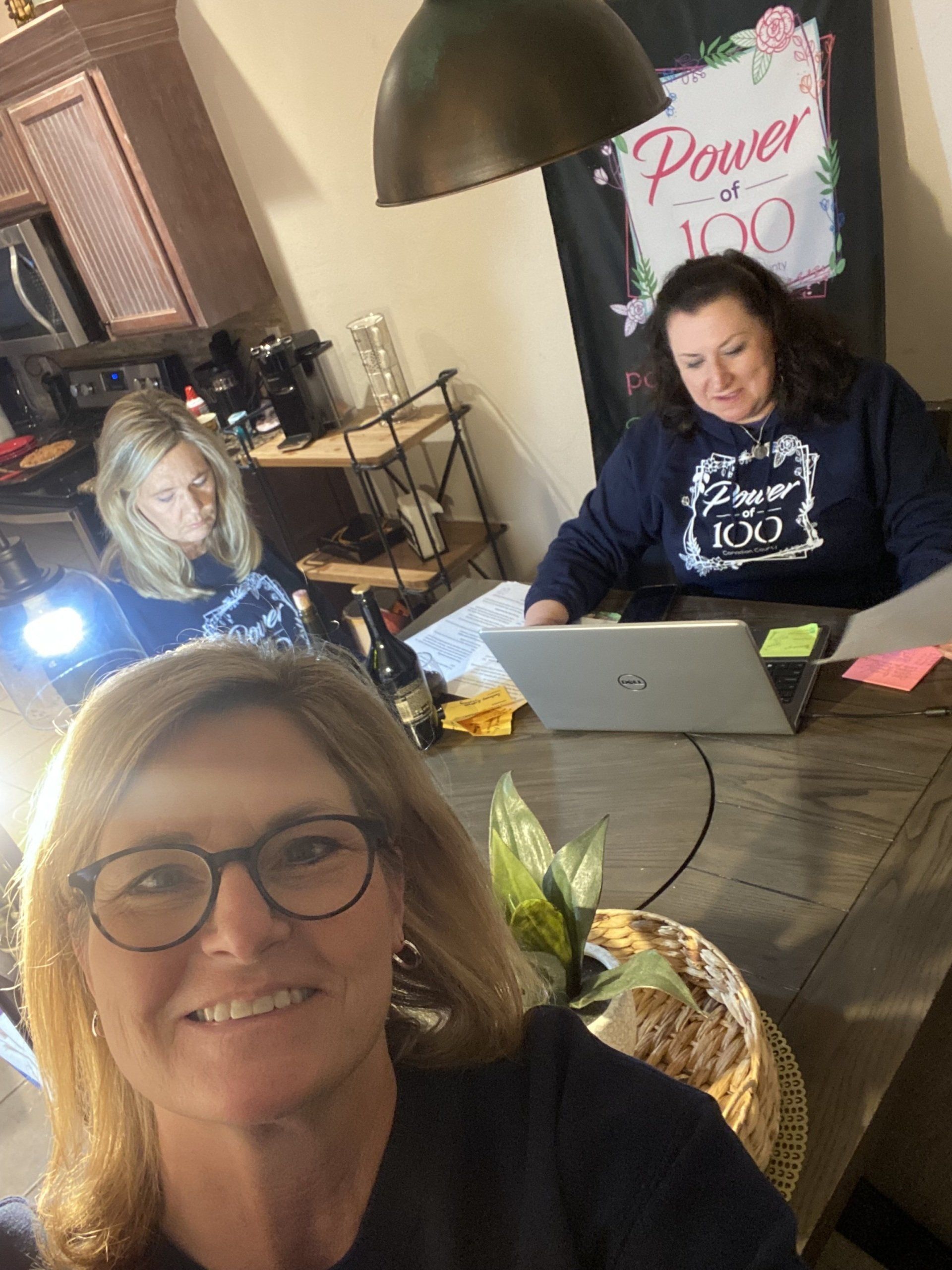 Three women are sitting at a table with laptops.