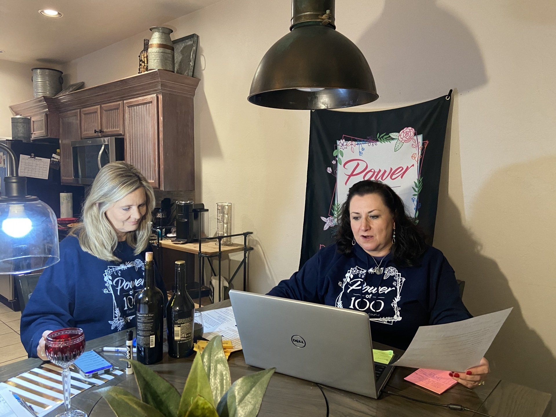 Two women are sitting at a table with a laptop.