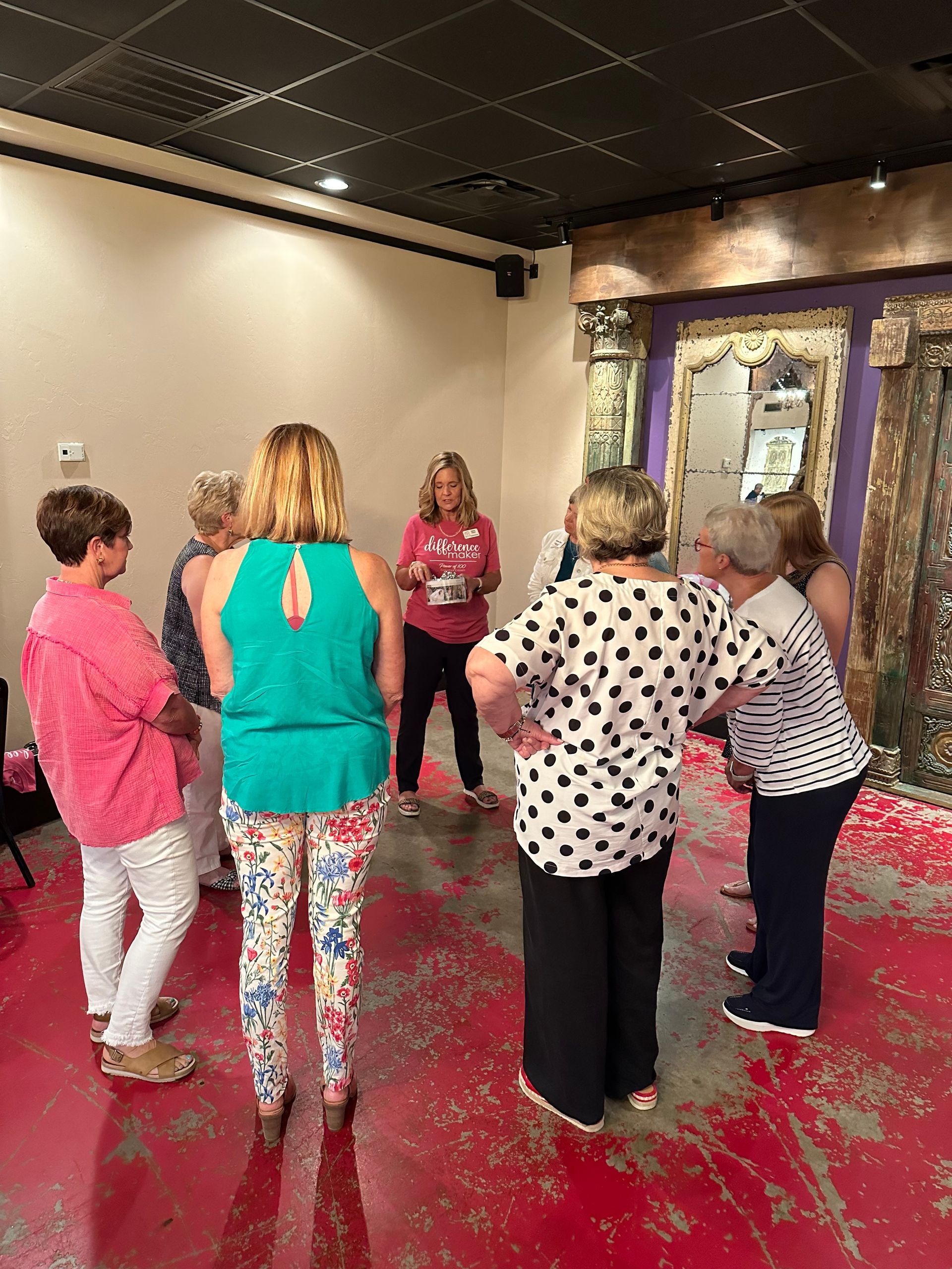 A group of women are standing in a circle in a room.