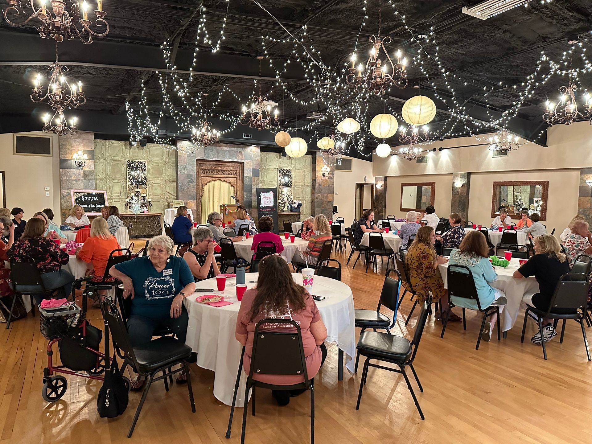 A large room filled with people sitting at tables and chairs.