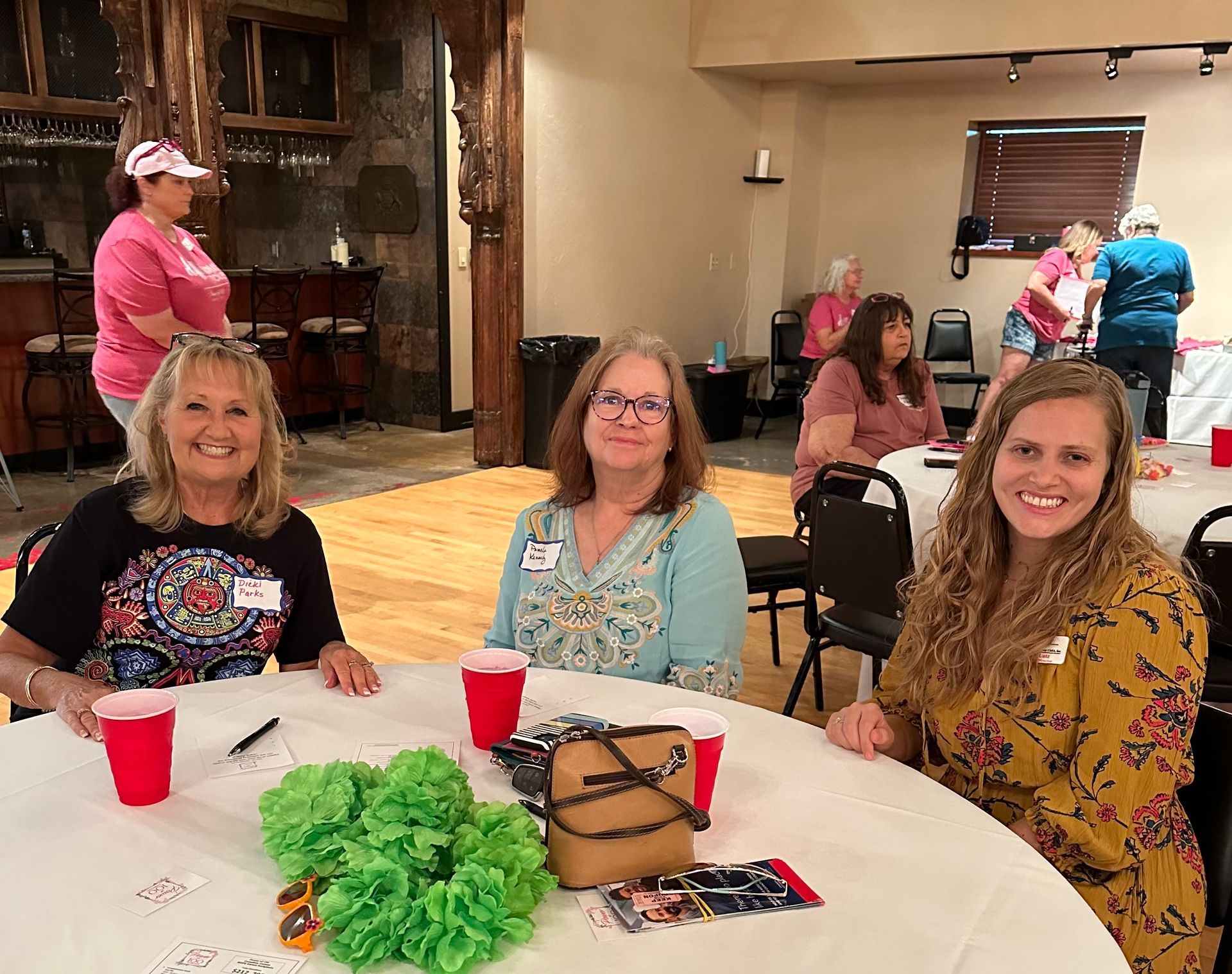 Three women are sitting at a table with red cups.
