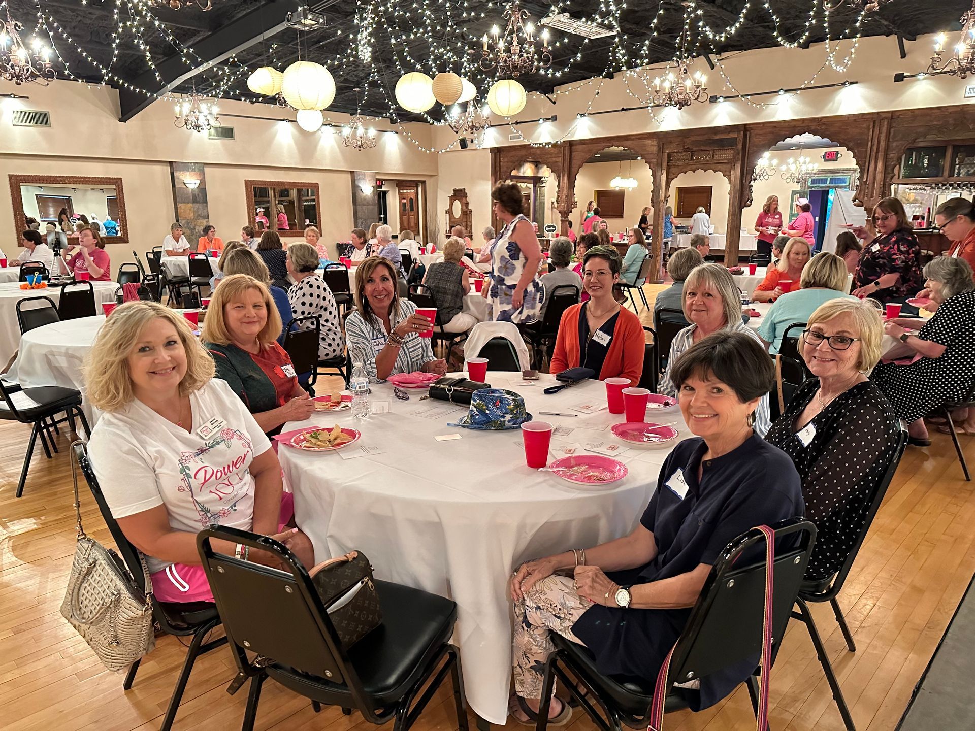 A group of women are sitting at tables in a large room.