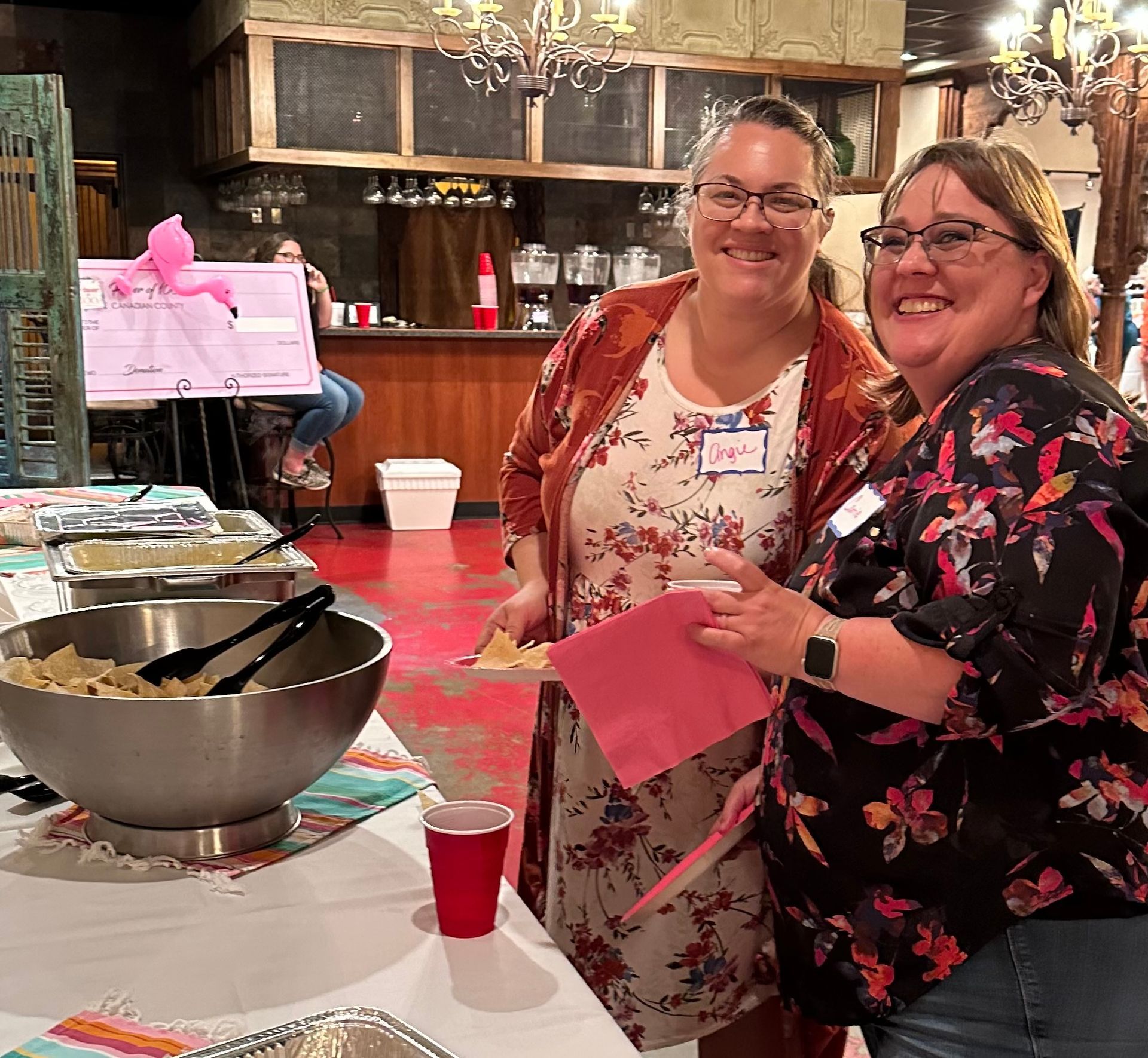 Two women are standing next to each other in front of a buffet table.