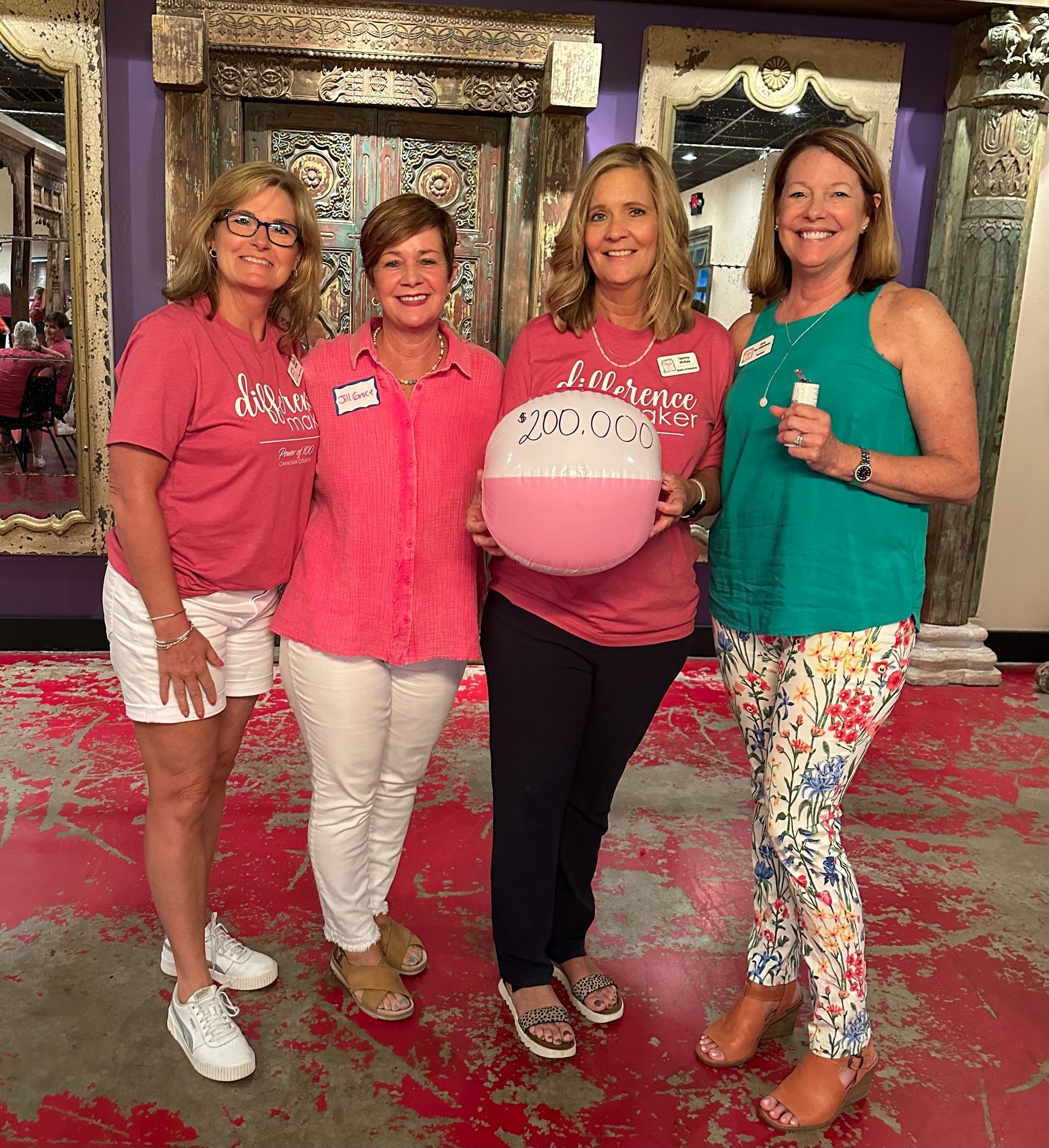 A group of women are standing next to each other holding a pink ball.