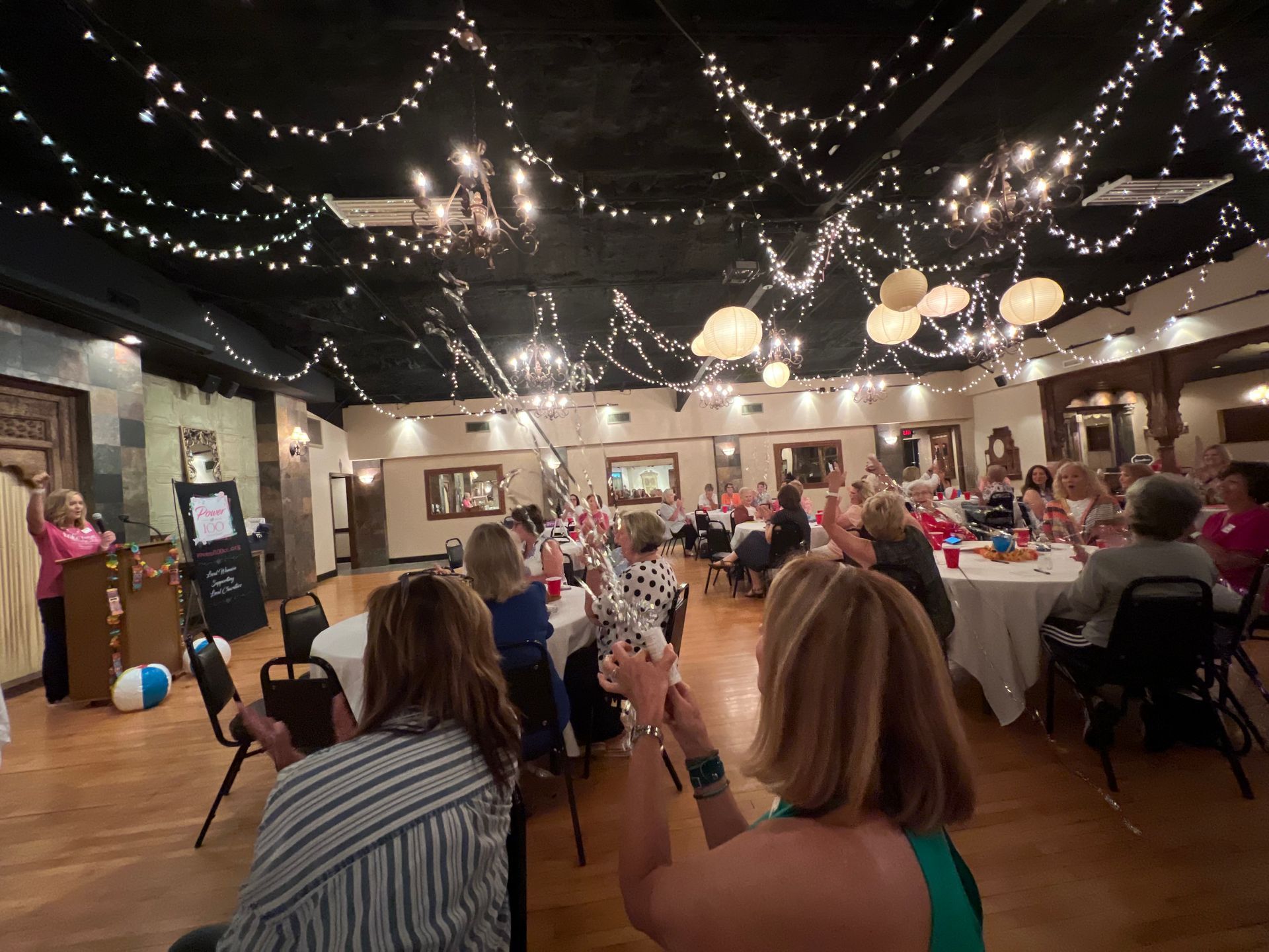 A group of people are sitting at tables in a large room.