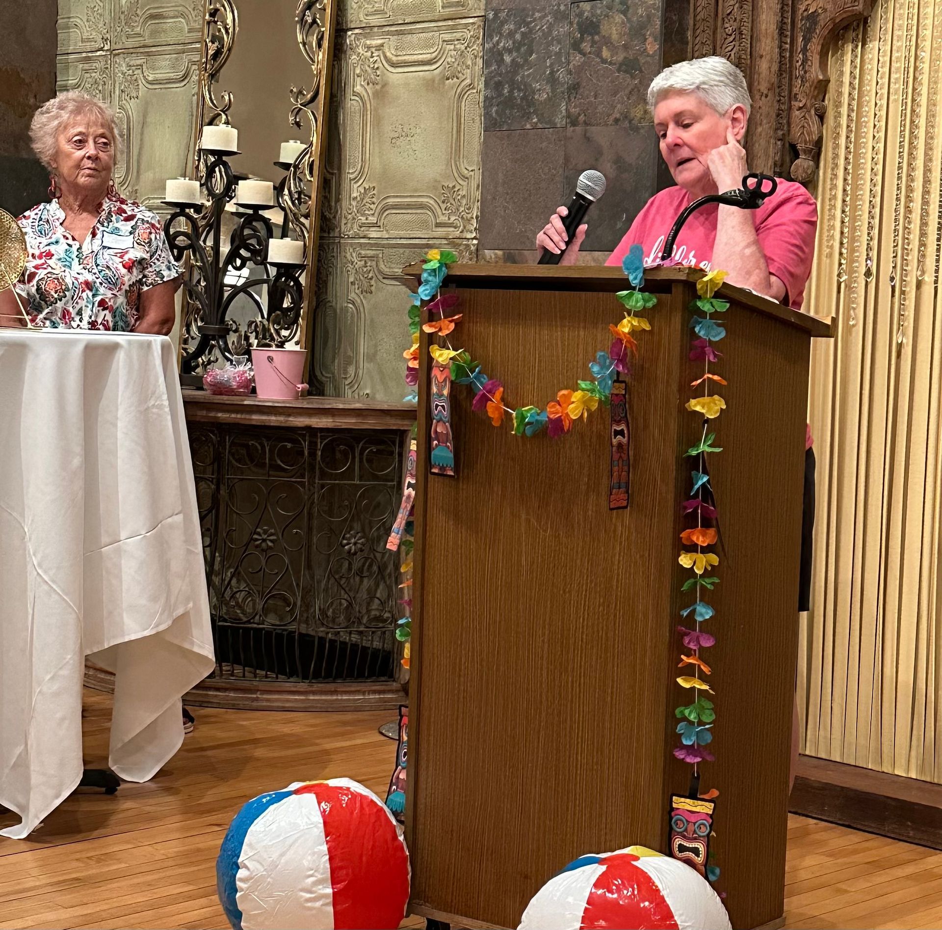A woman stands at a podium holding a microphone