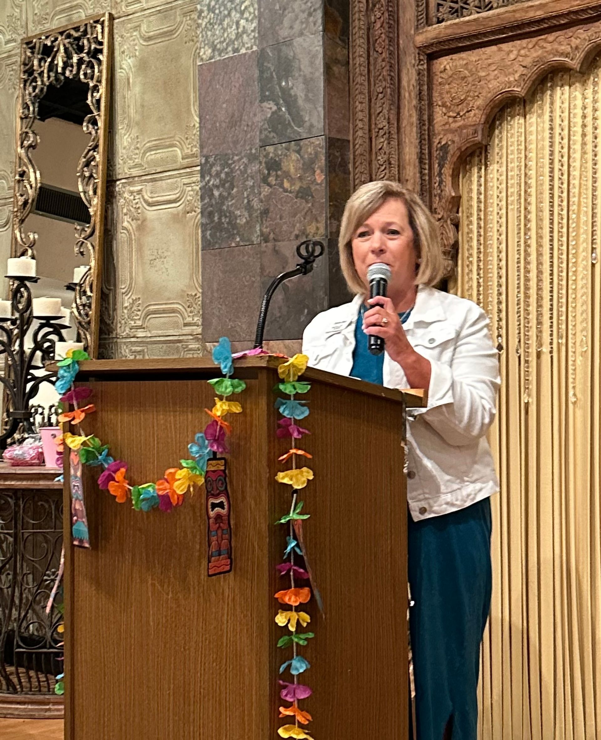 A woman is standing at a podium holding a microphone.