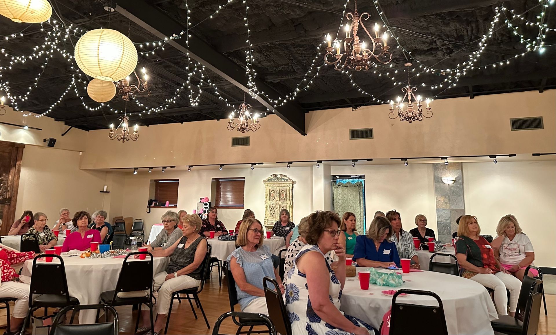 A group of people are sitting at tables in a large room.
