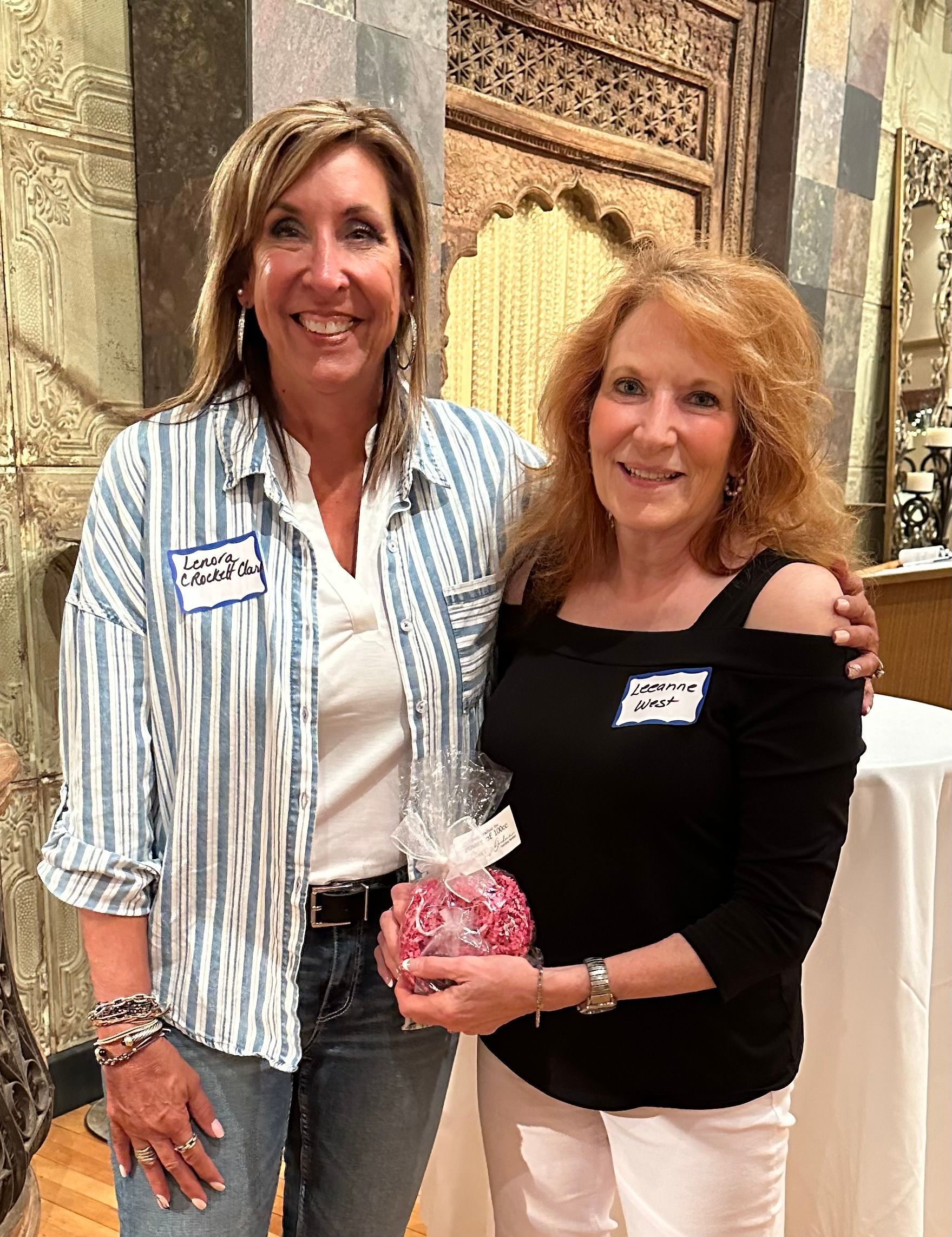 Two women are posing for a picture and one of them is holding a gift.