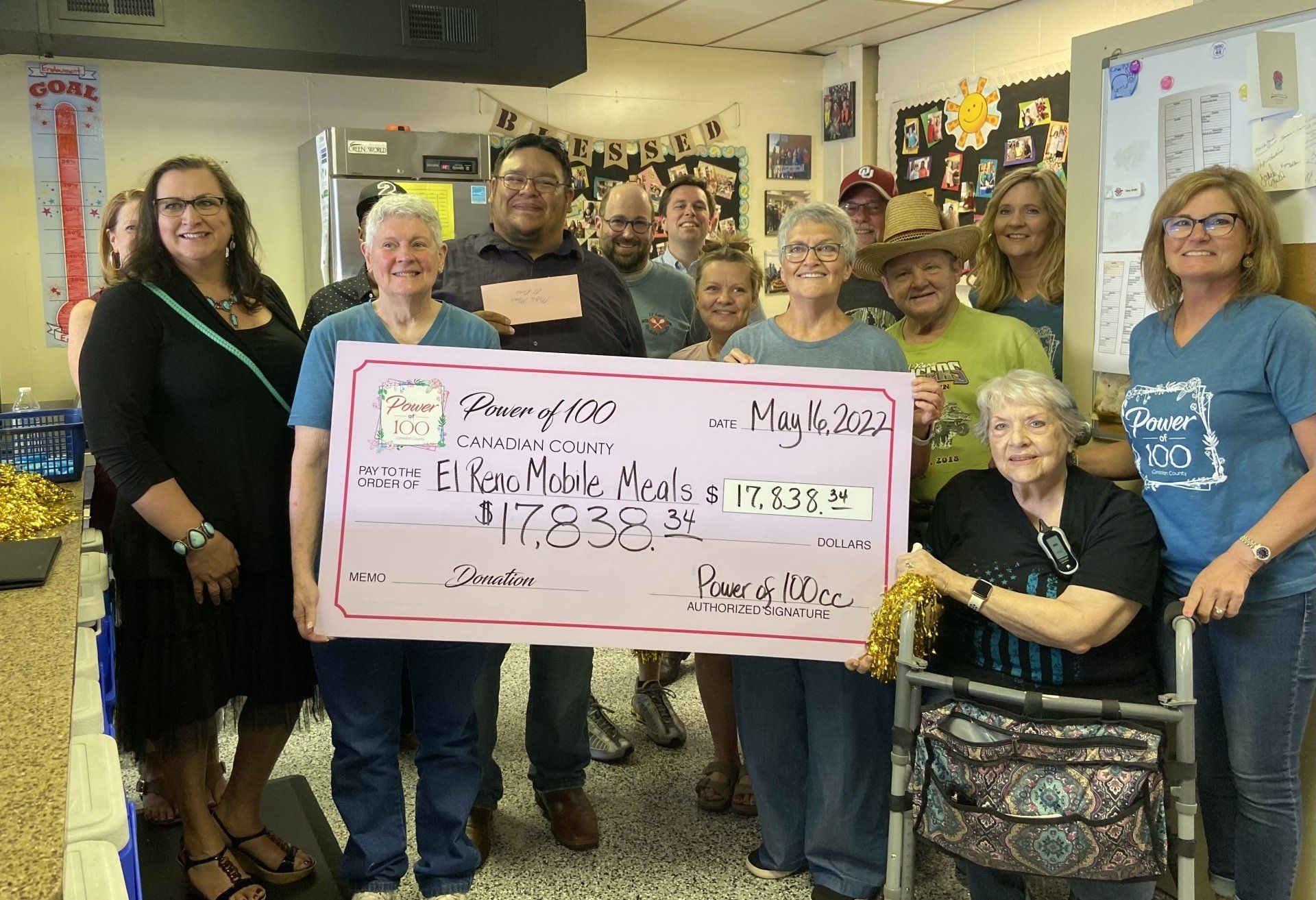 A group of people are standing around a large check.