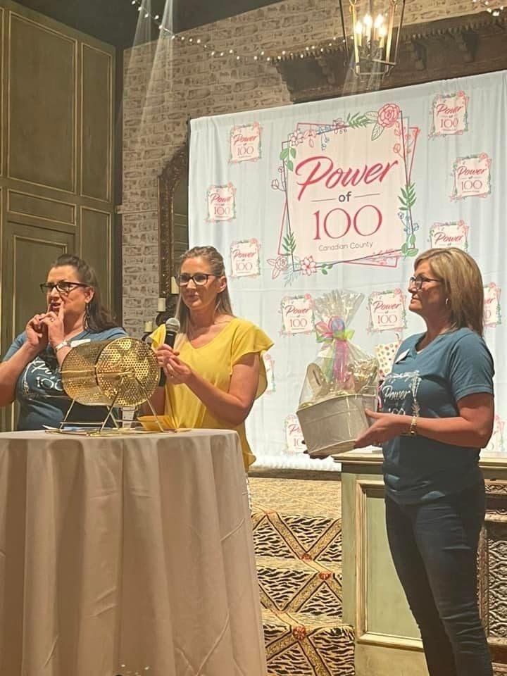 Three women are standing next to each other on a stage holding microphones.