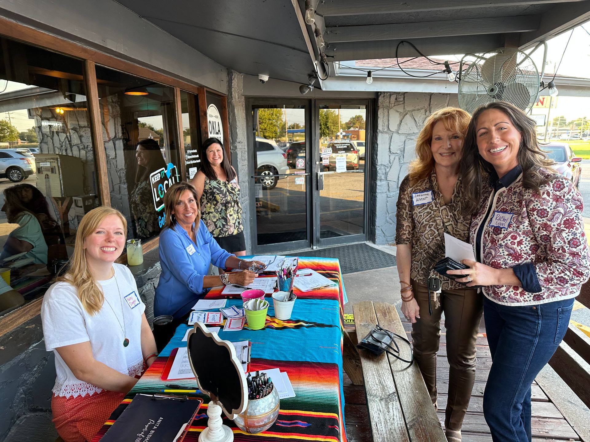 A group of women are standing around a table in front of a building.