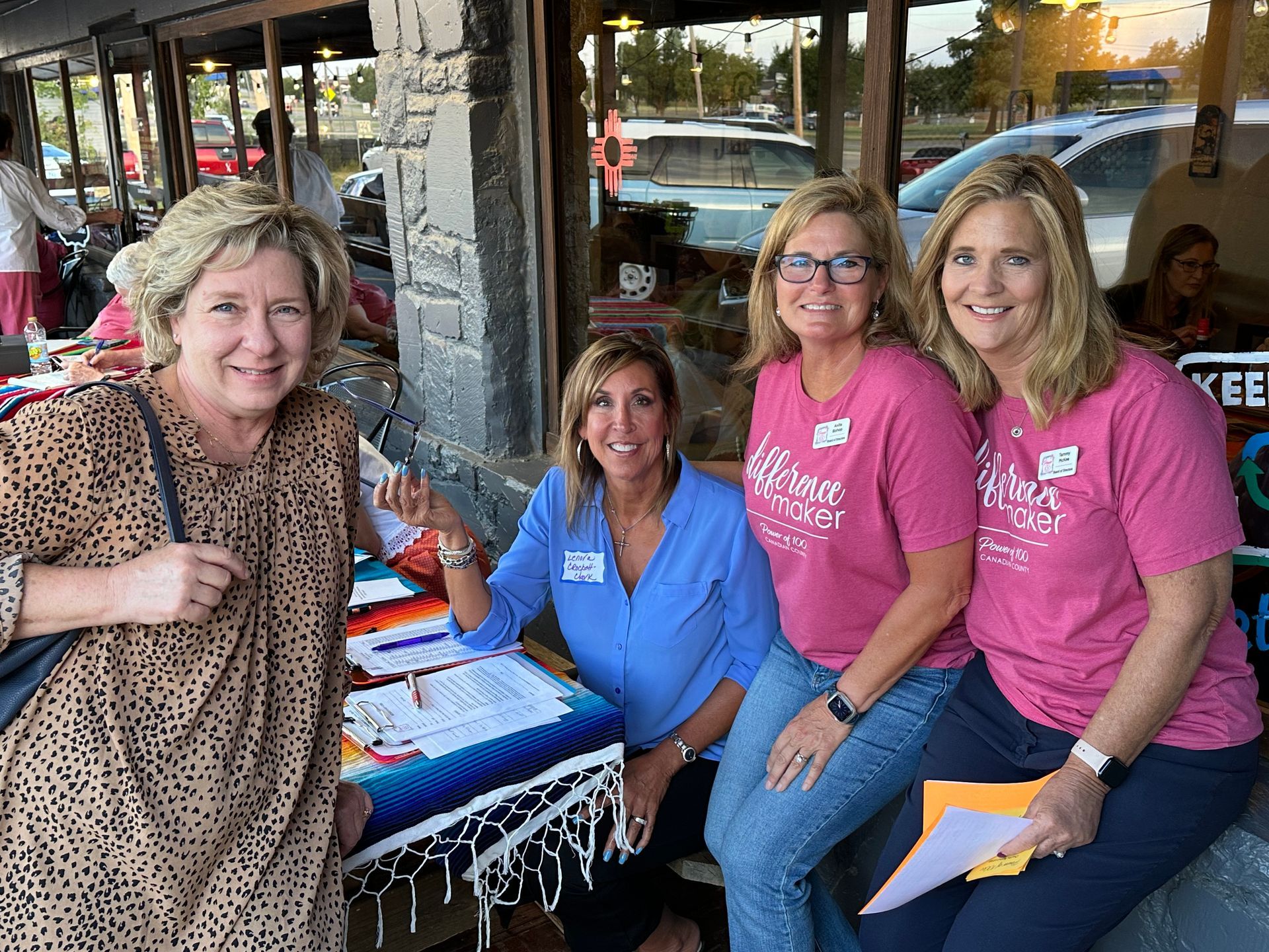 A group of women are posing for a picture while sitting at a table.