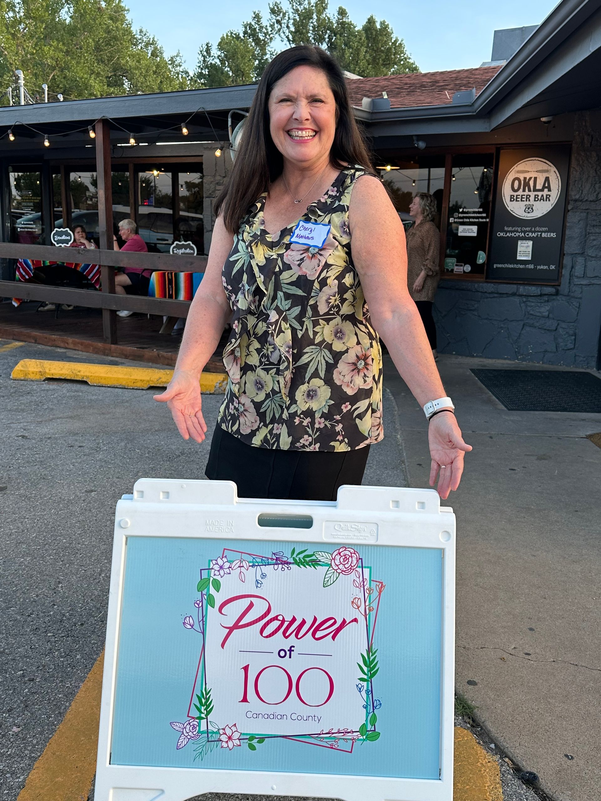 A woman is standing next to a sign that says power of 100