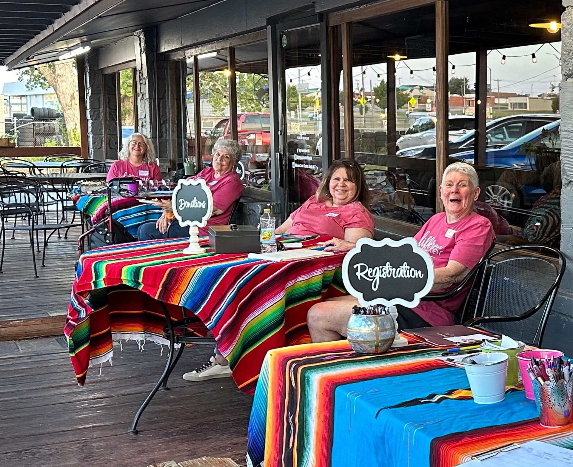 A group of women are sitting at tables outside of a restaurant.
