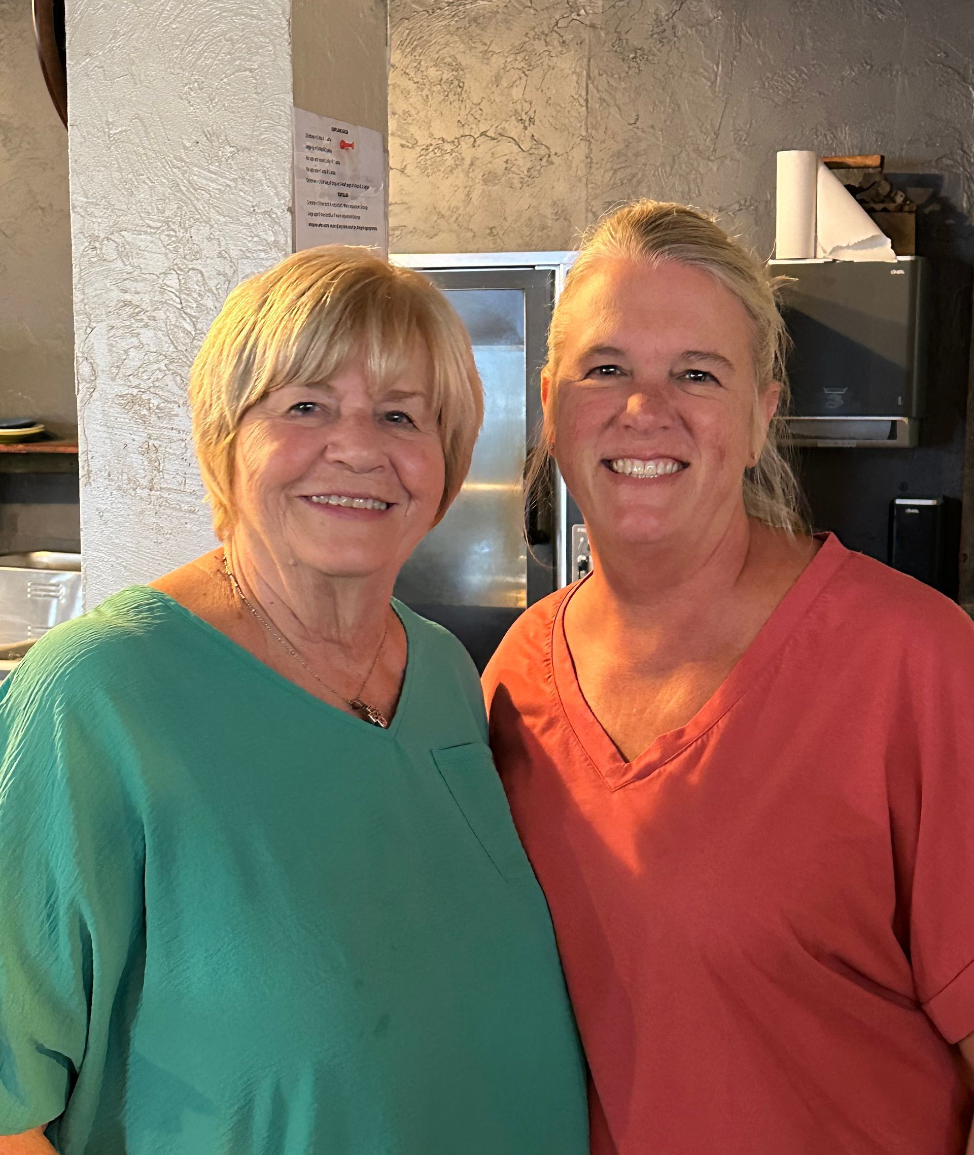 Two women are posing for a picture together and smiling for the camera.