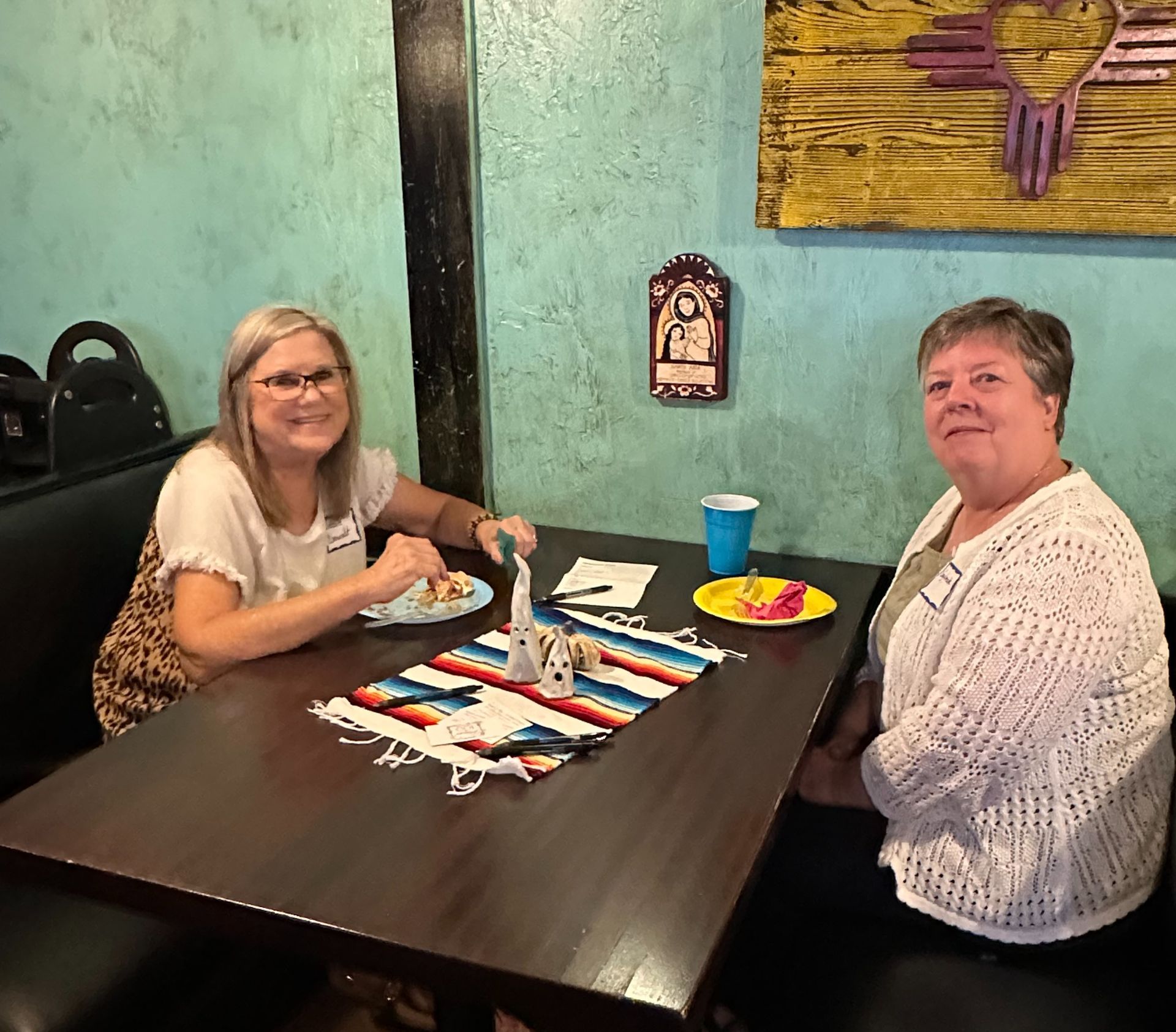 Two women are sitting at a table in a restaurant eating food.