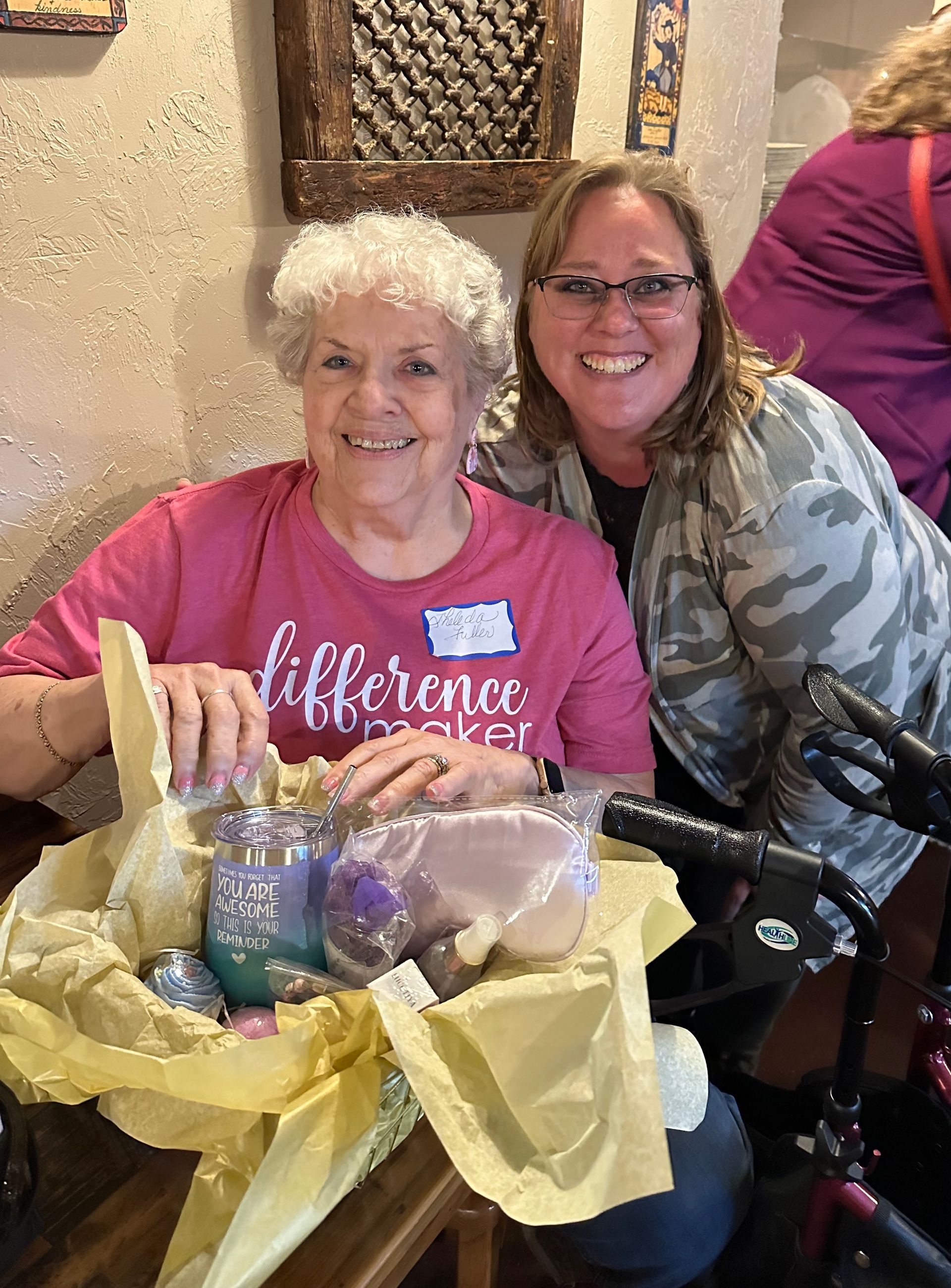 Two women are posing for a picture while sitting at a table.