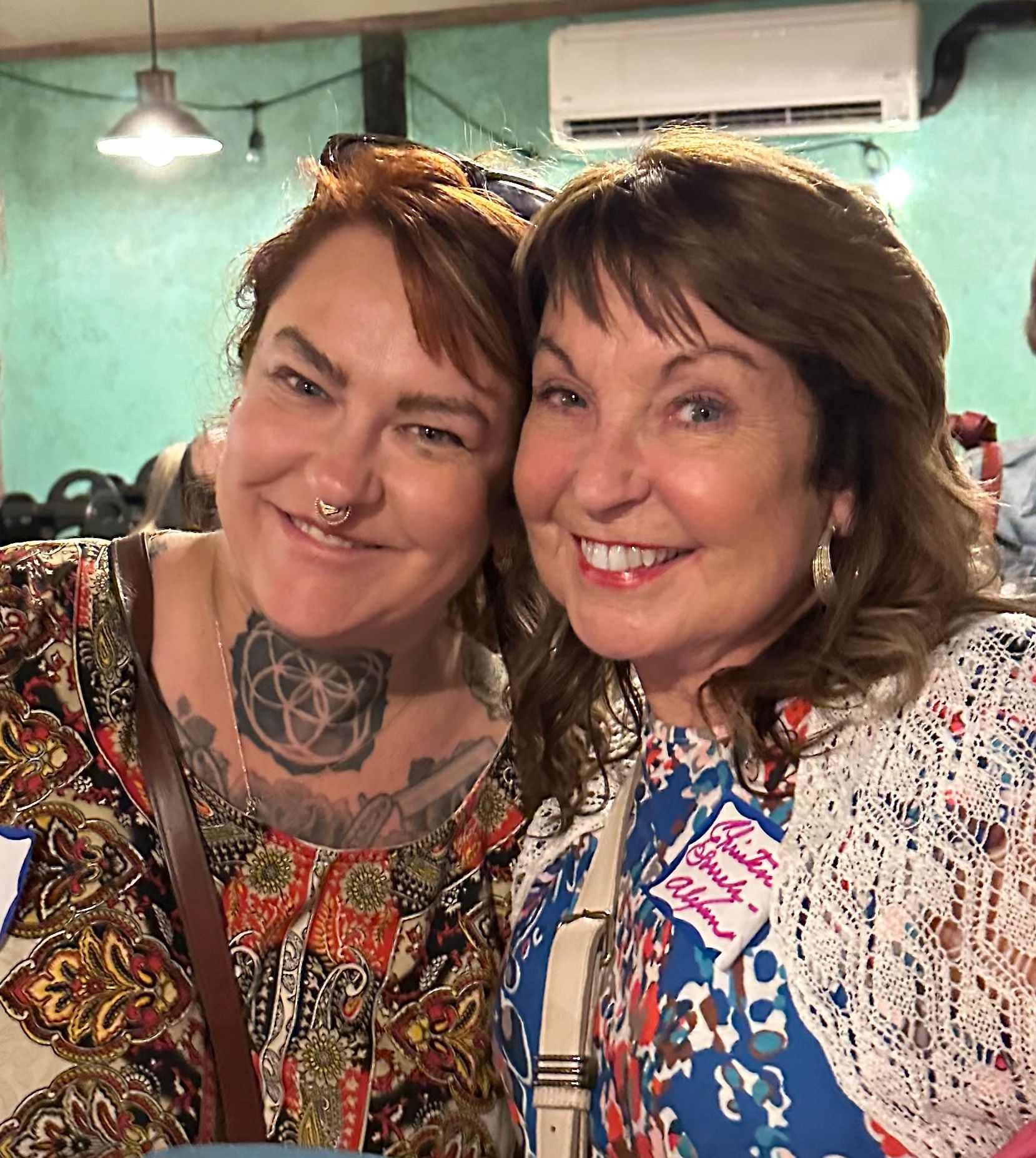 Two women are posing for a picture together and smiling for the camera.
