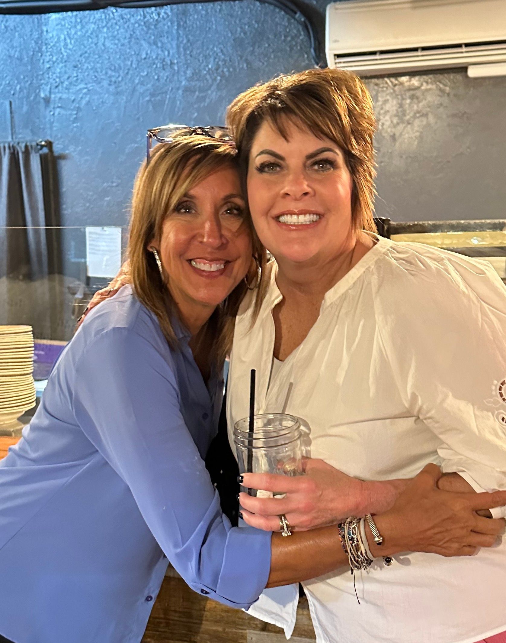 Two women are hugging each other and smiling for the camera.