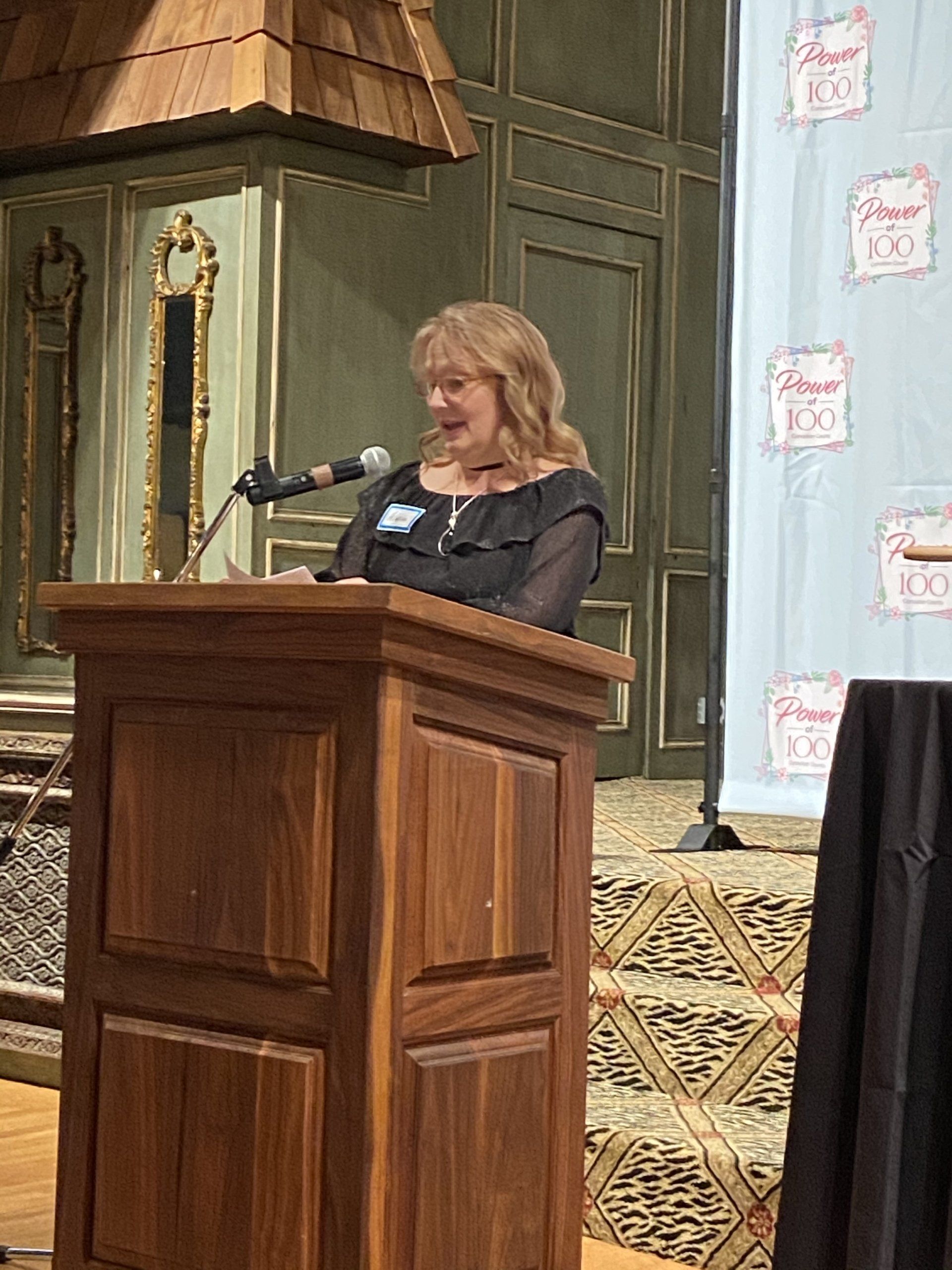 A woman is standing at a podium speaking into a microphone.