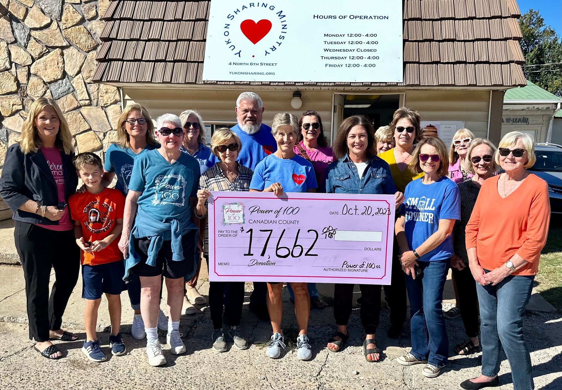 A group of people are standing in front of a building holding a large check.