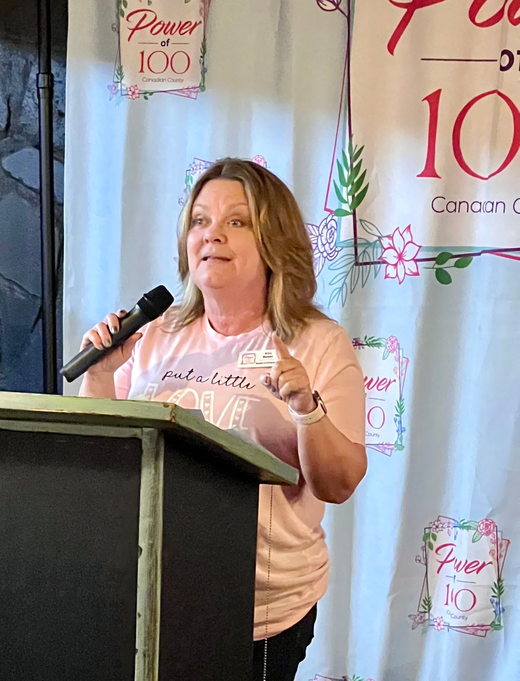 A woman is standing at a podium holding a microphone.