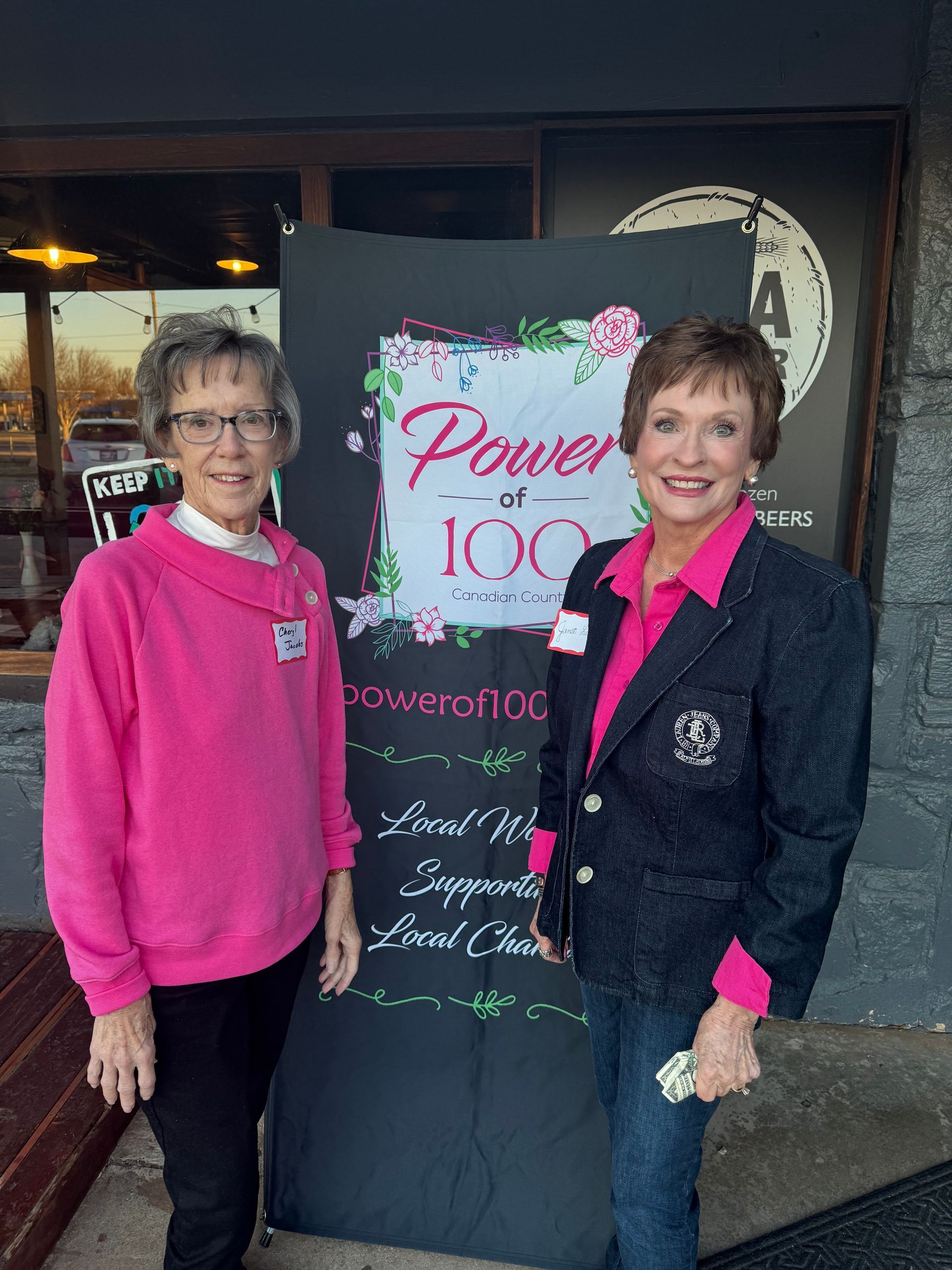 Two women are standing in front of a sign that says power of 100
