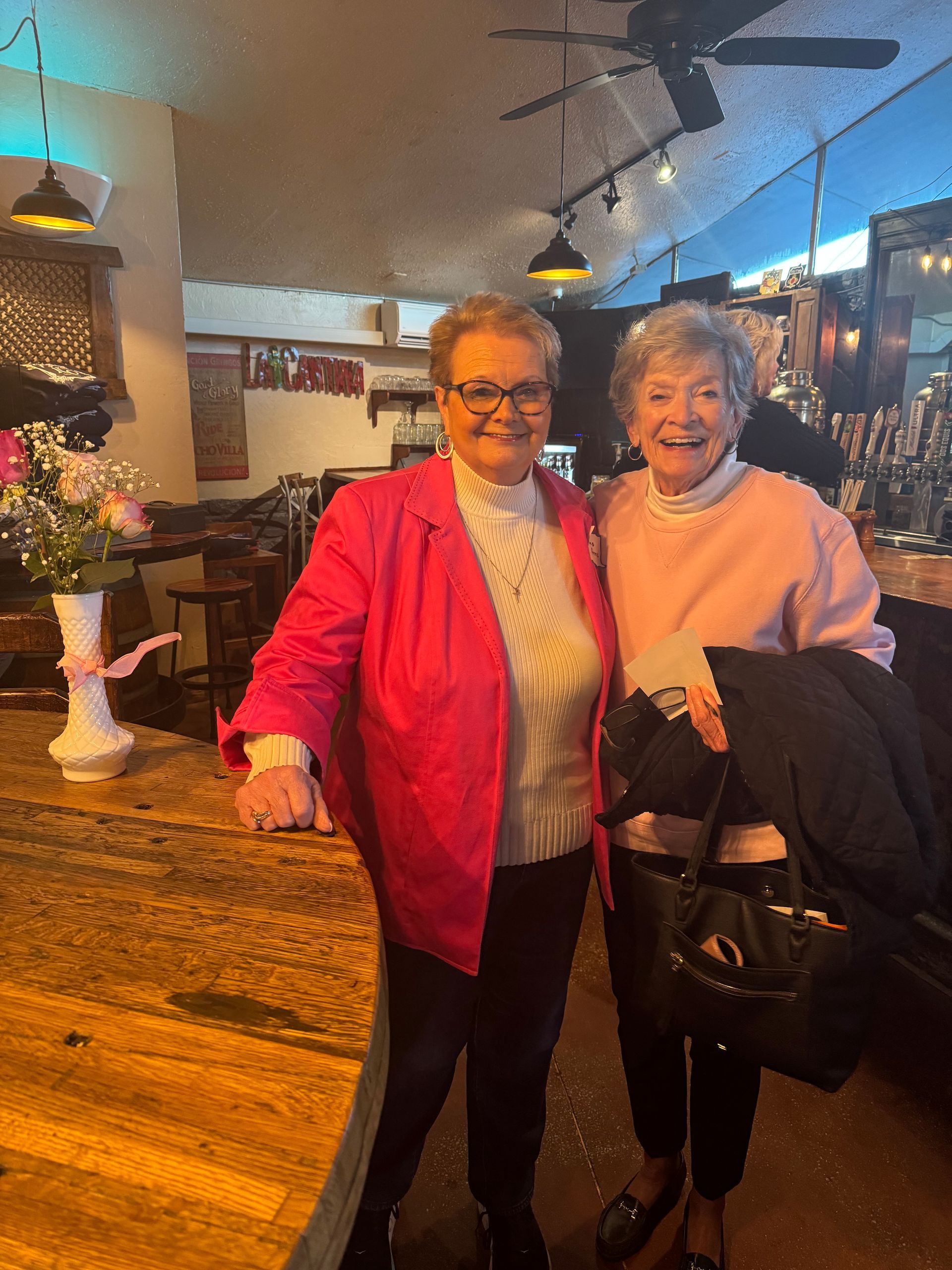 Two older women are posing for a picture in a restaurant.