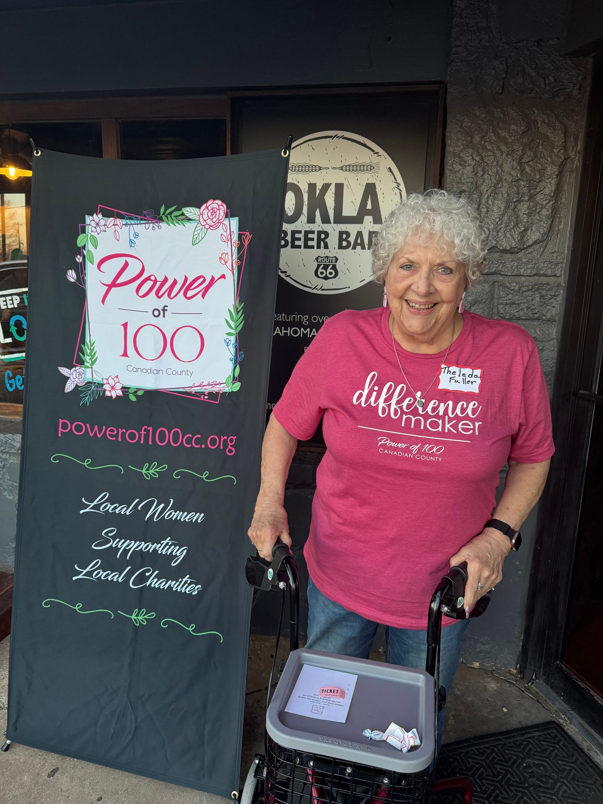 An elderly woman is standing in front of a sign that says power at 100.