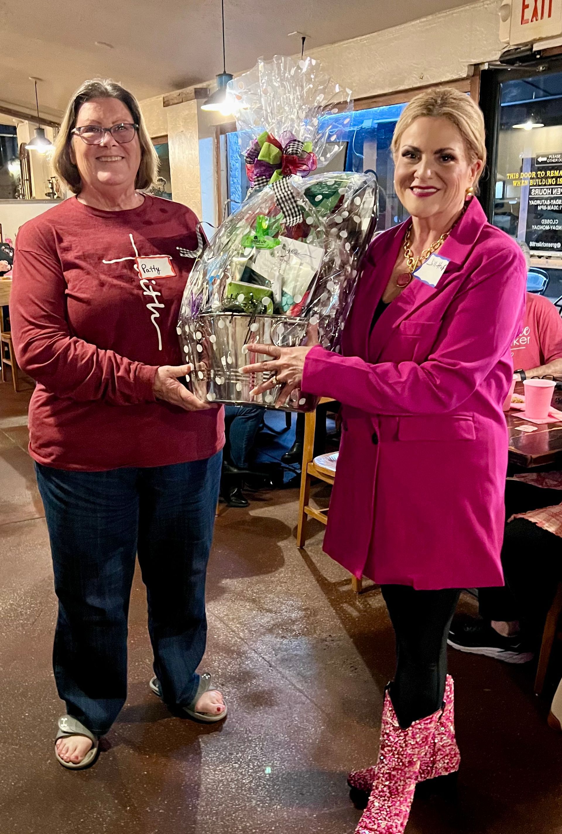 Two women are standing next to each other in a restaurant holding a bouquet of flowers.