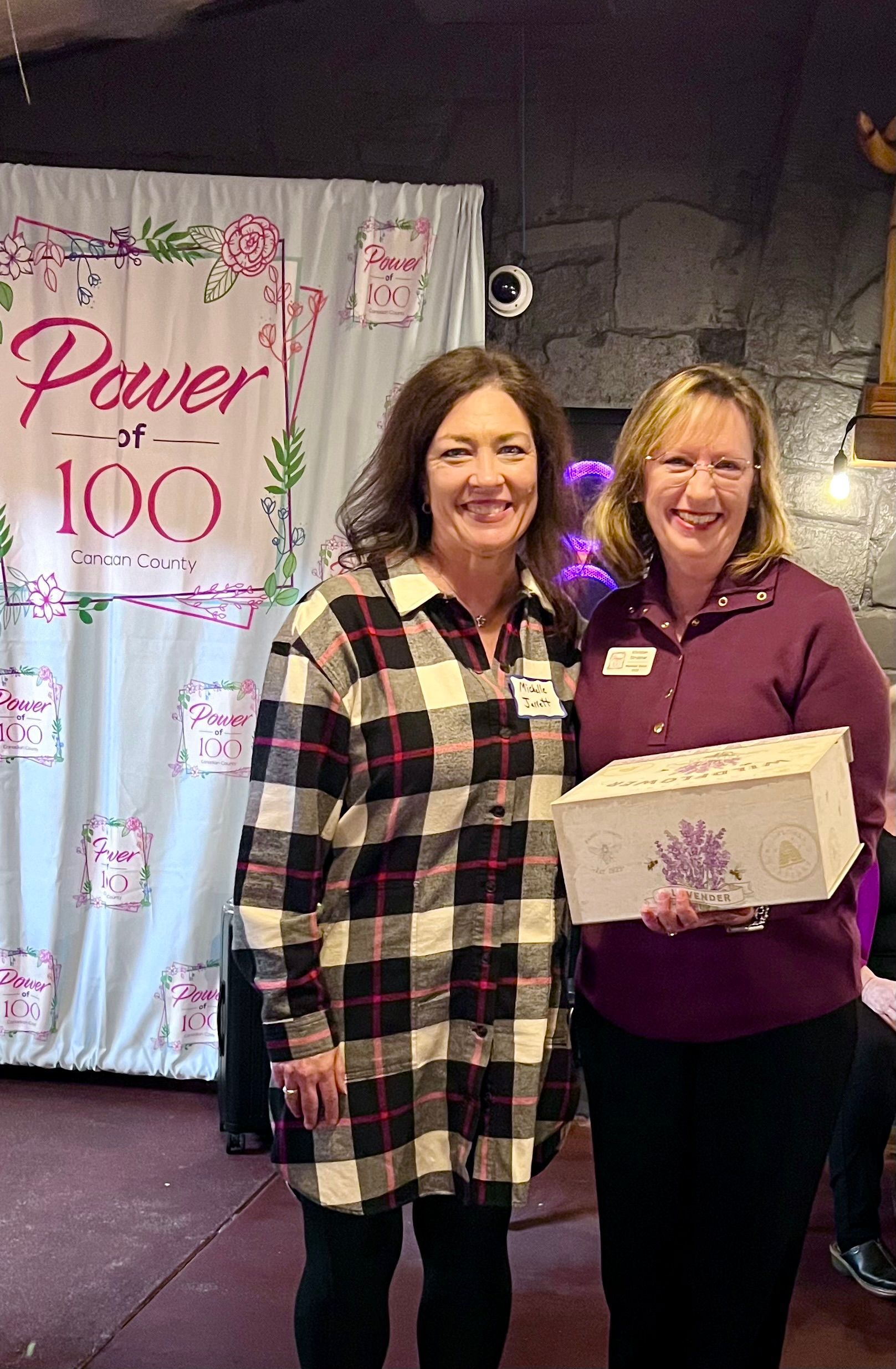 Two women are standing next to each other in front of a sign that says `` power 100 ''.