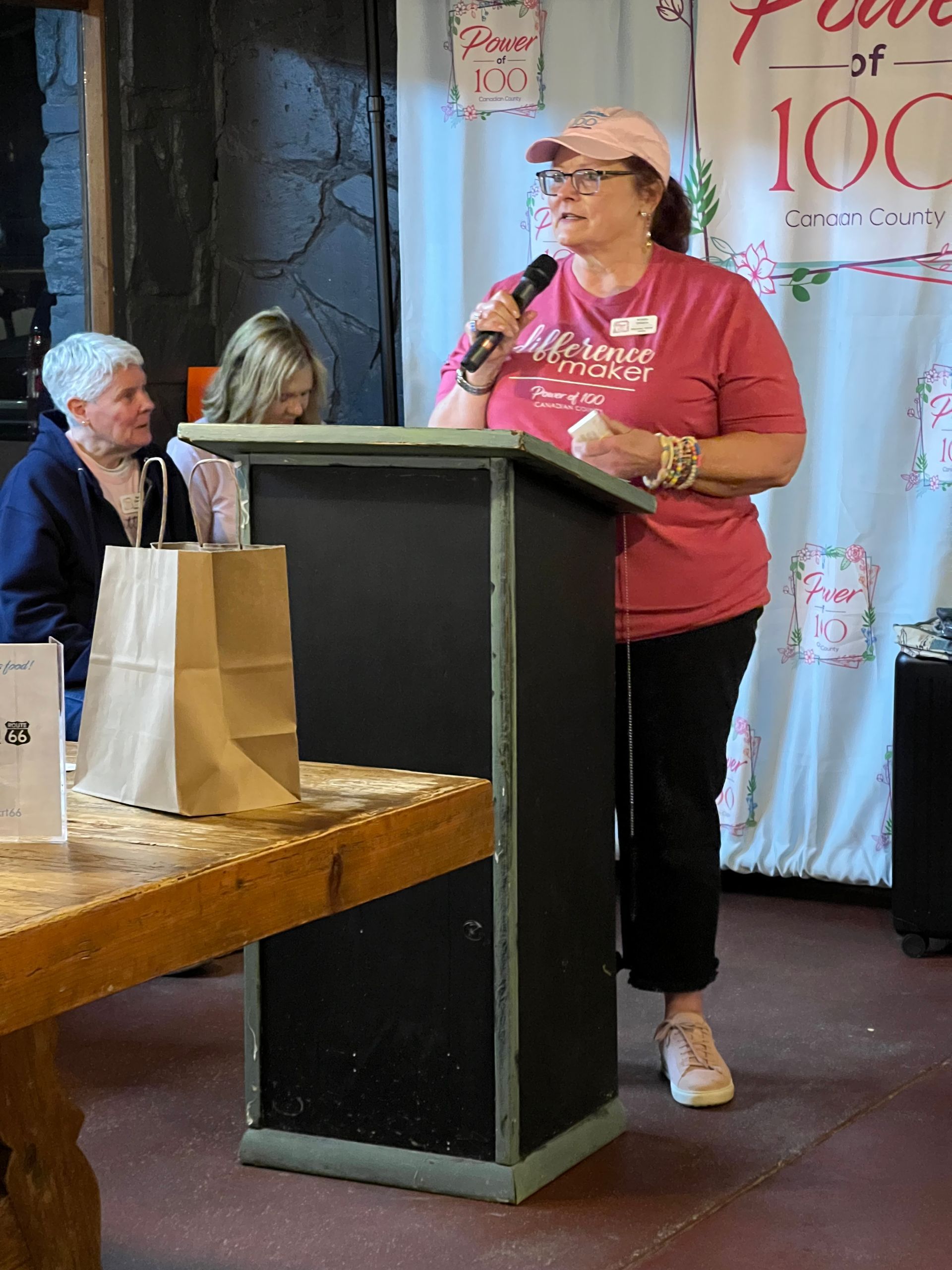 A woman stands at a podium speaking into a microphone