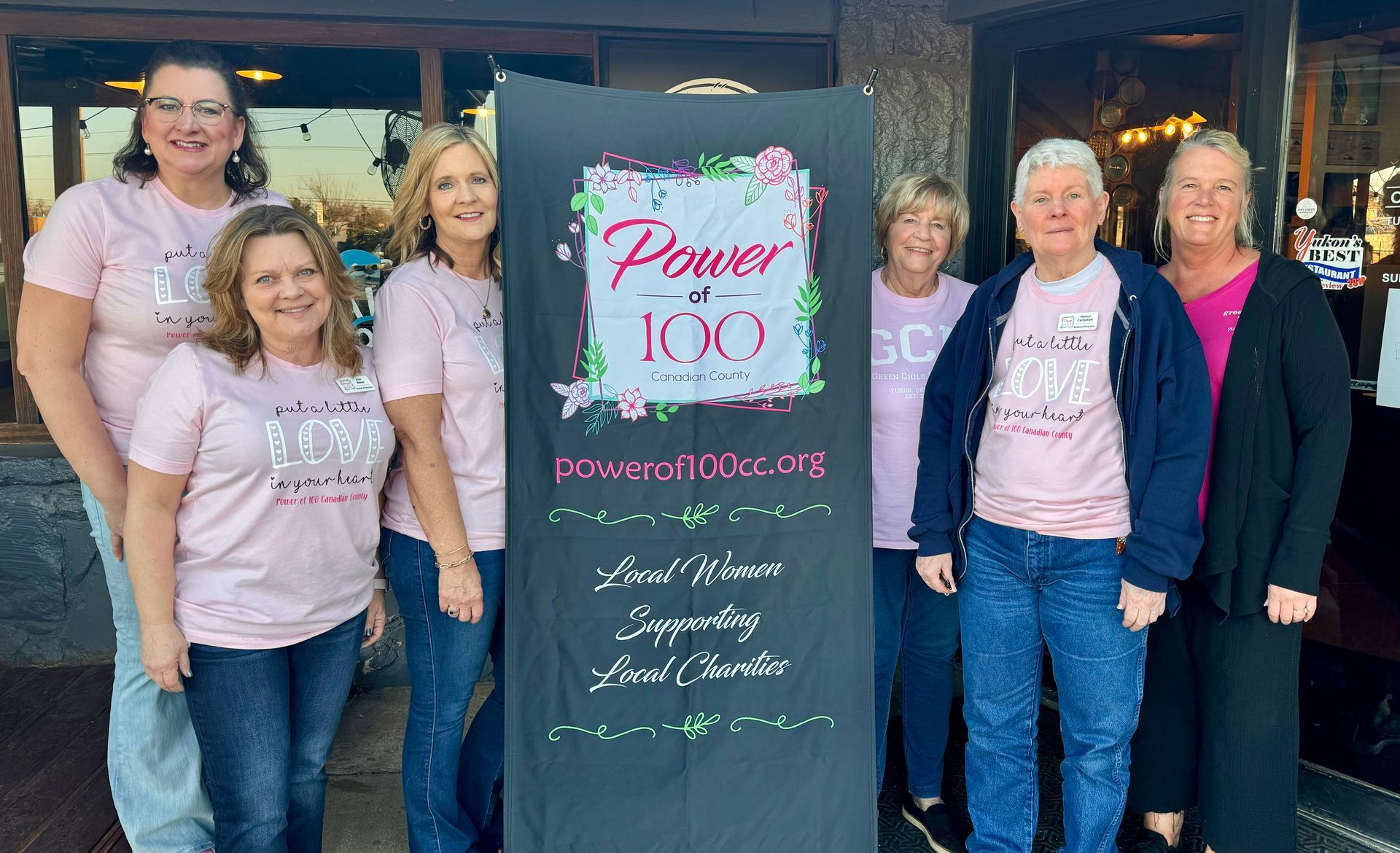 A group of people standing in front of a sign that says power 100.