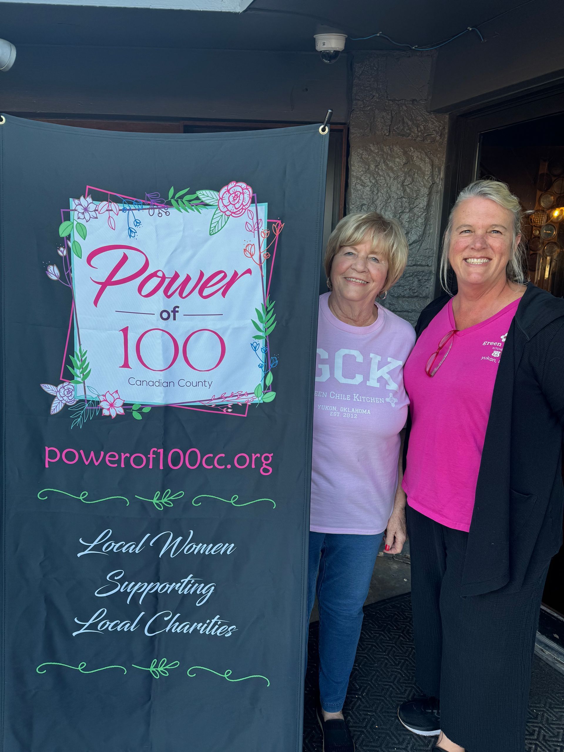 Two women are standing next to each other in front of a sign that says power of 100.