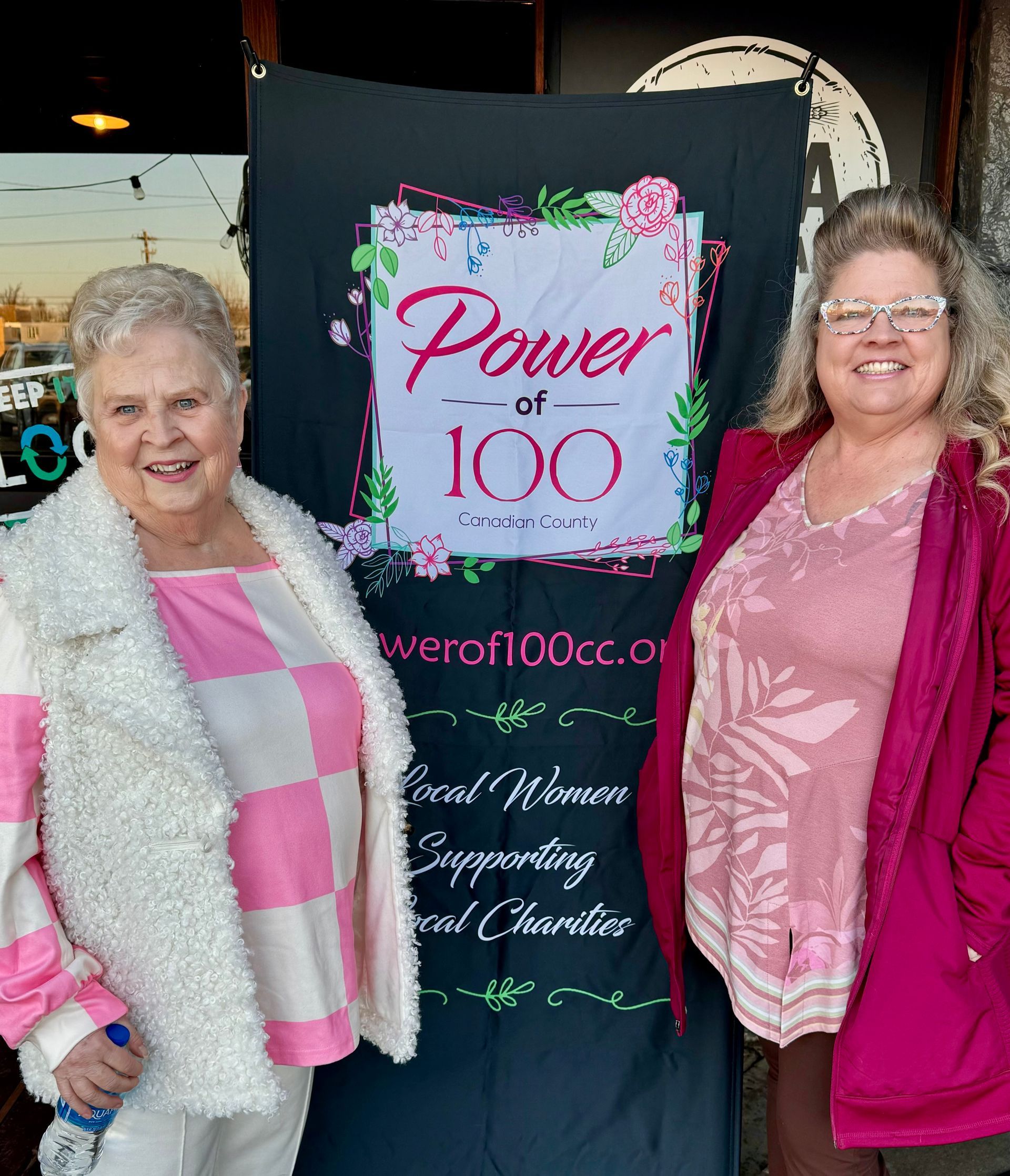 Two women are standing in front of a sign that says power of 100