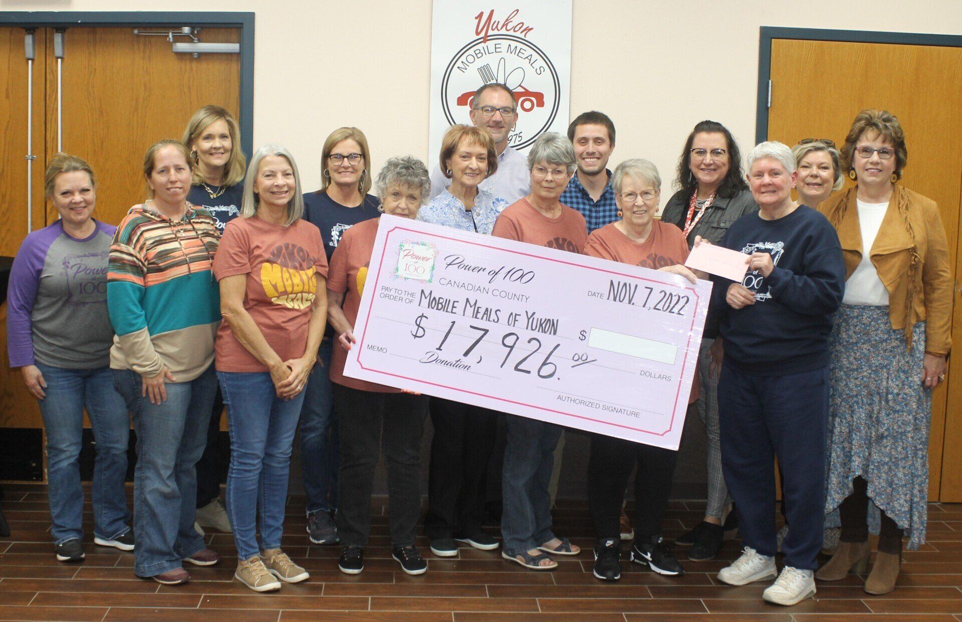 A group of people standing around a large check.