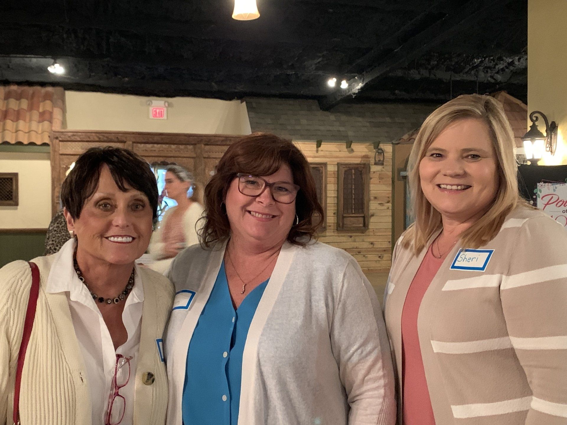 Three women are posing for a picture together and smiling.