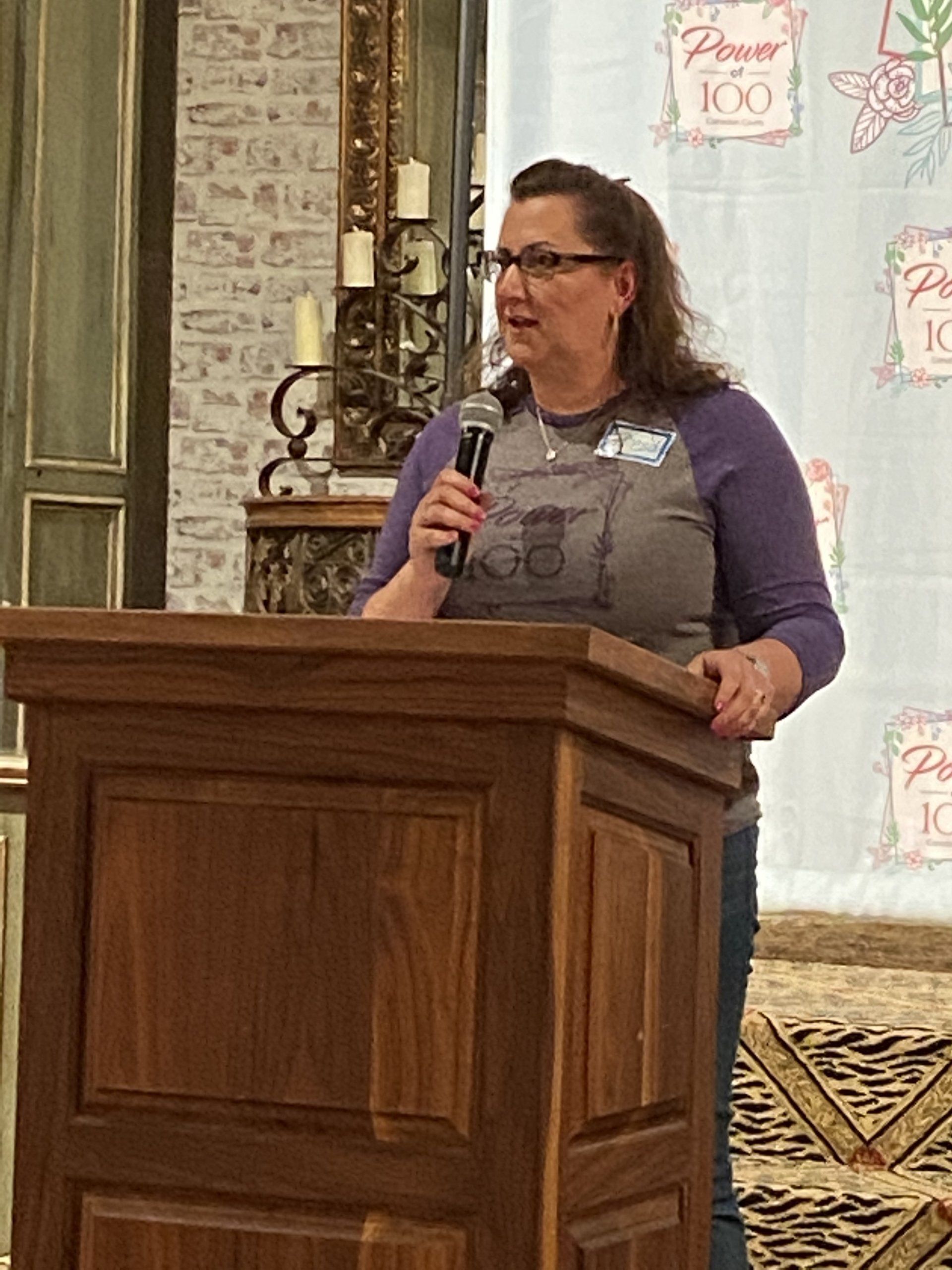A woman is standing at a podium holding a microphone.
