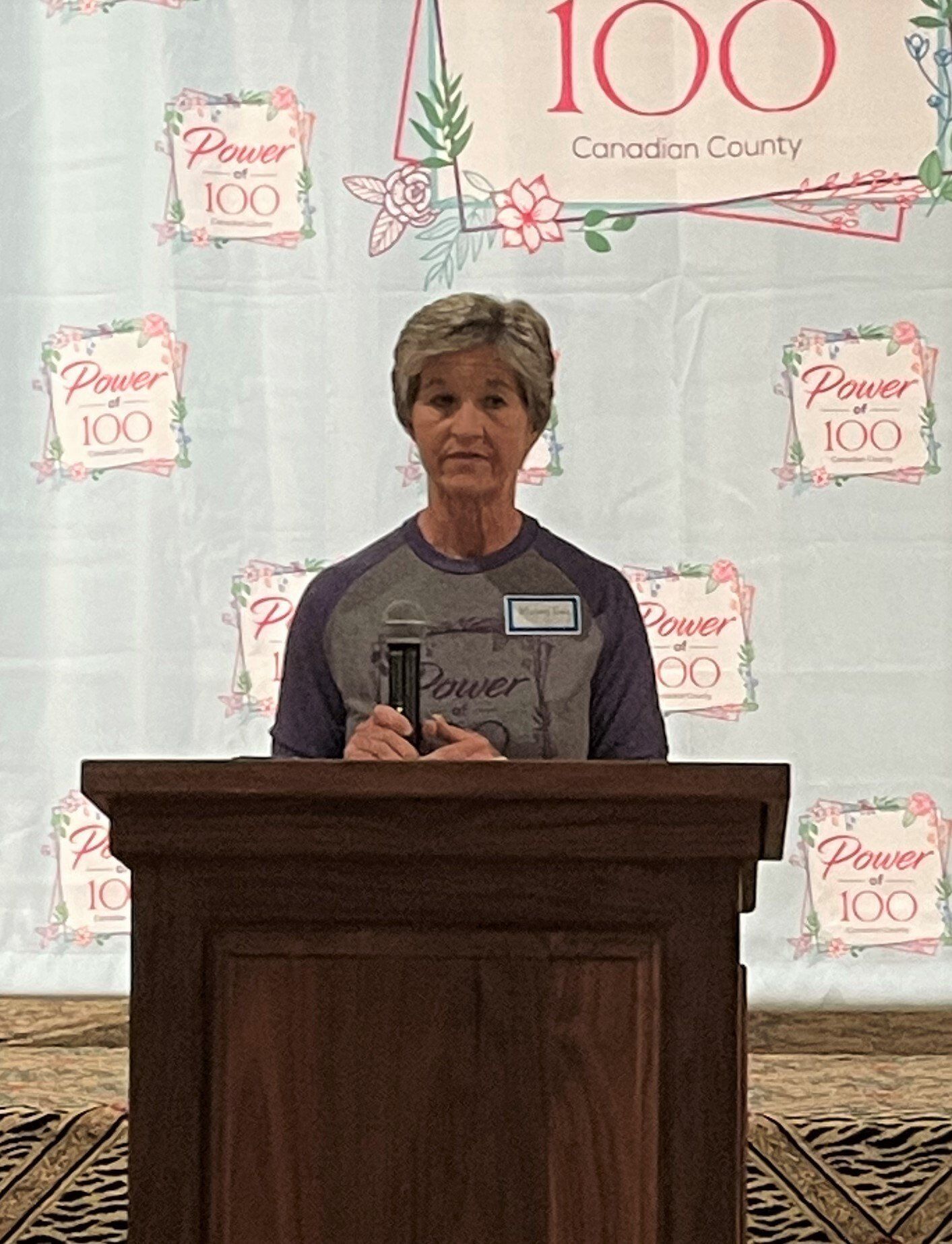 A woman is standing at a podium holding a microphone.