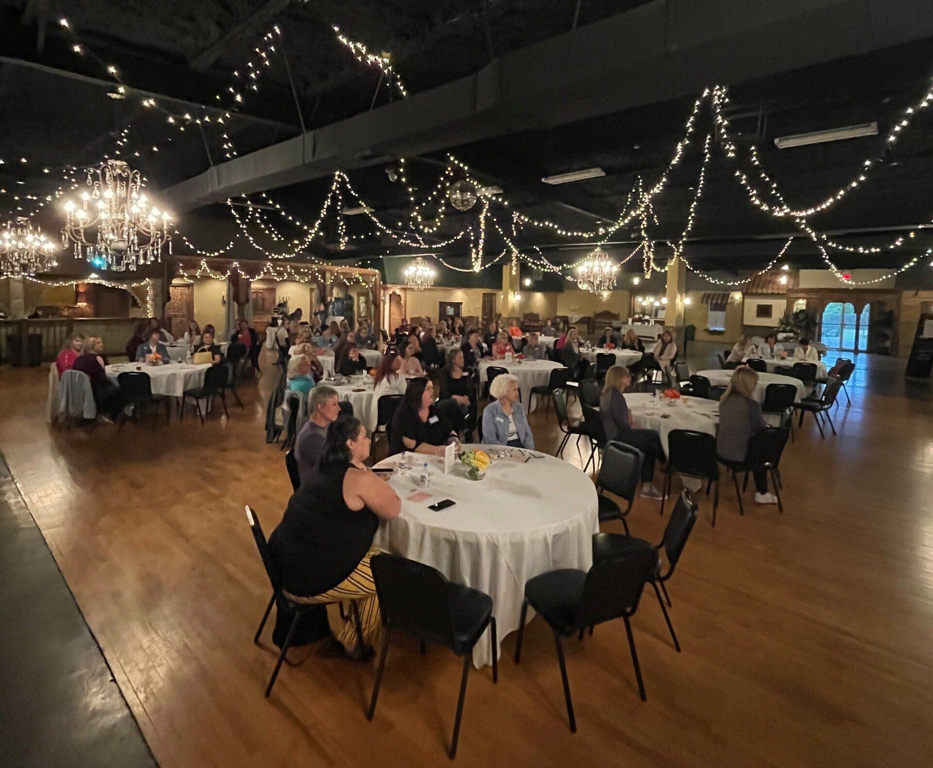 A large group of people are sitting at tables in a large room.