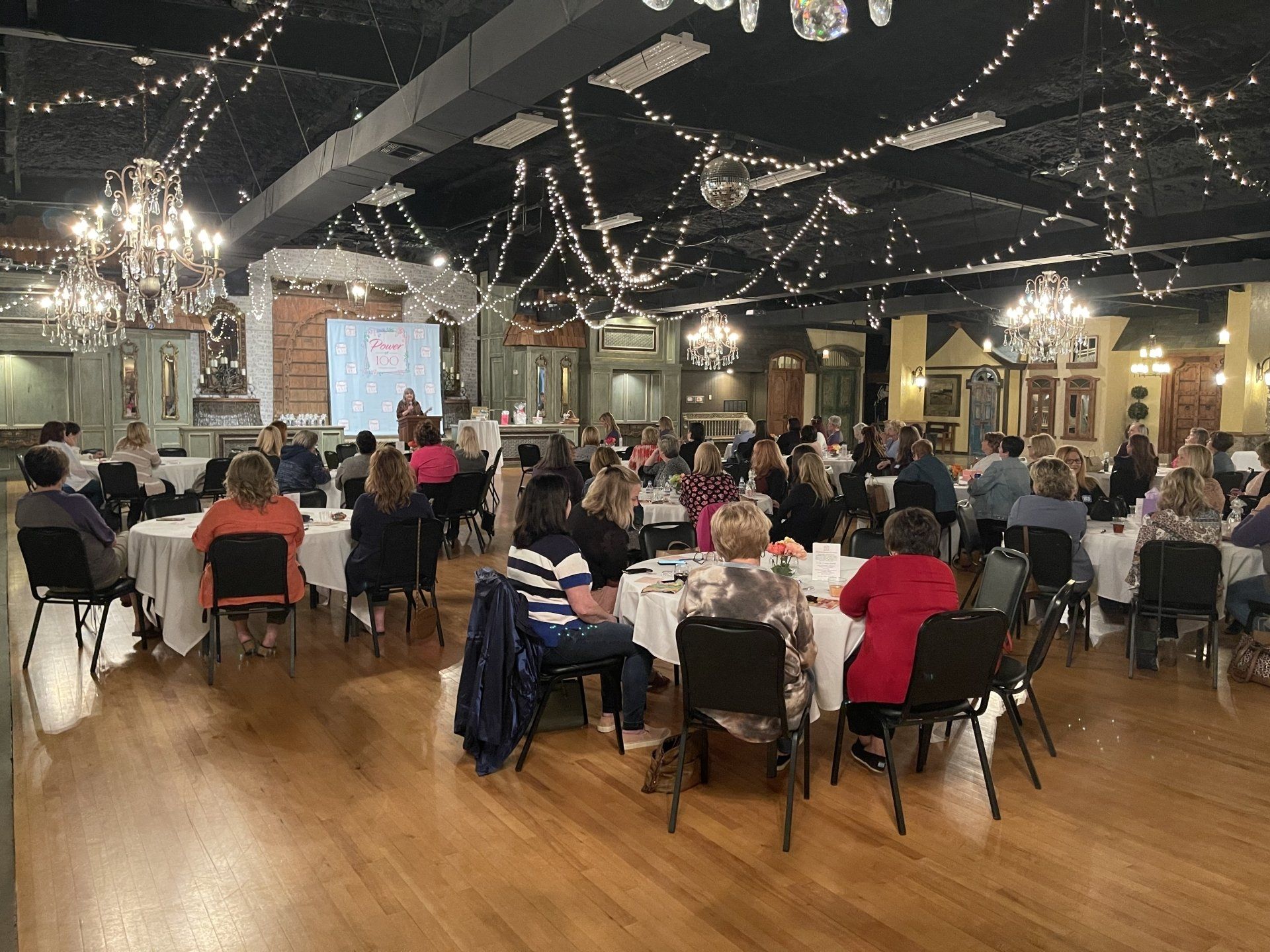 A large group of people are sitting at tables in a large room.