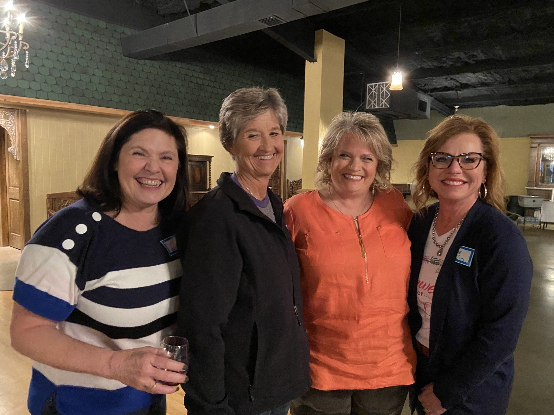 Four women are posing for a picture together in a room.